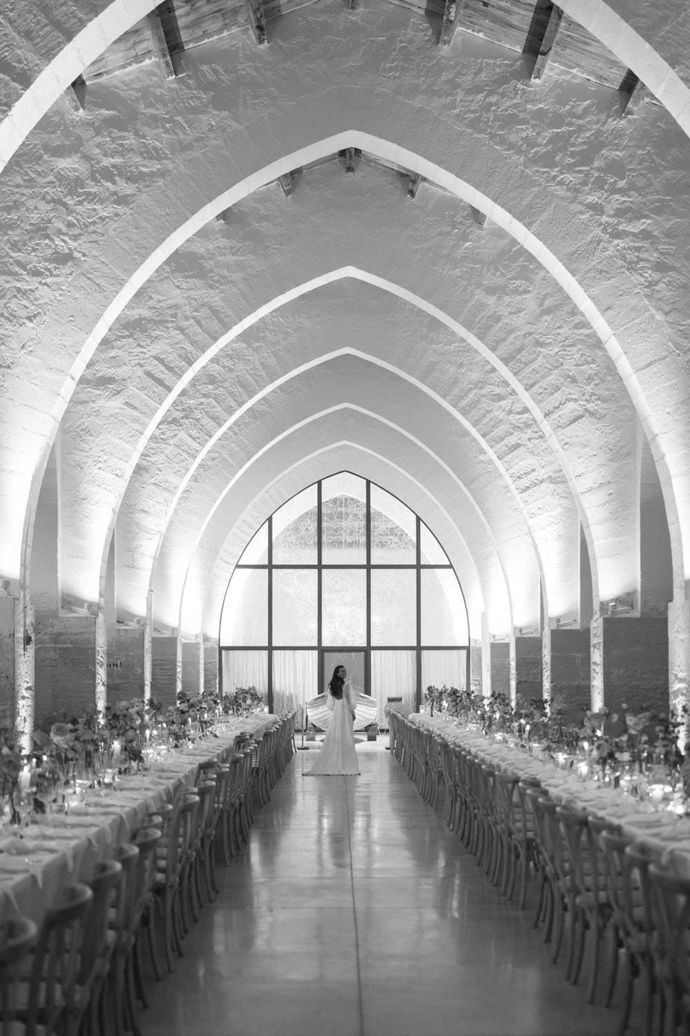 Grand vaulted reception hall with arched ceilings and long banquet tables set for an elegant wedding.