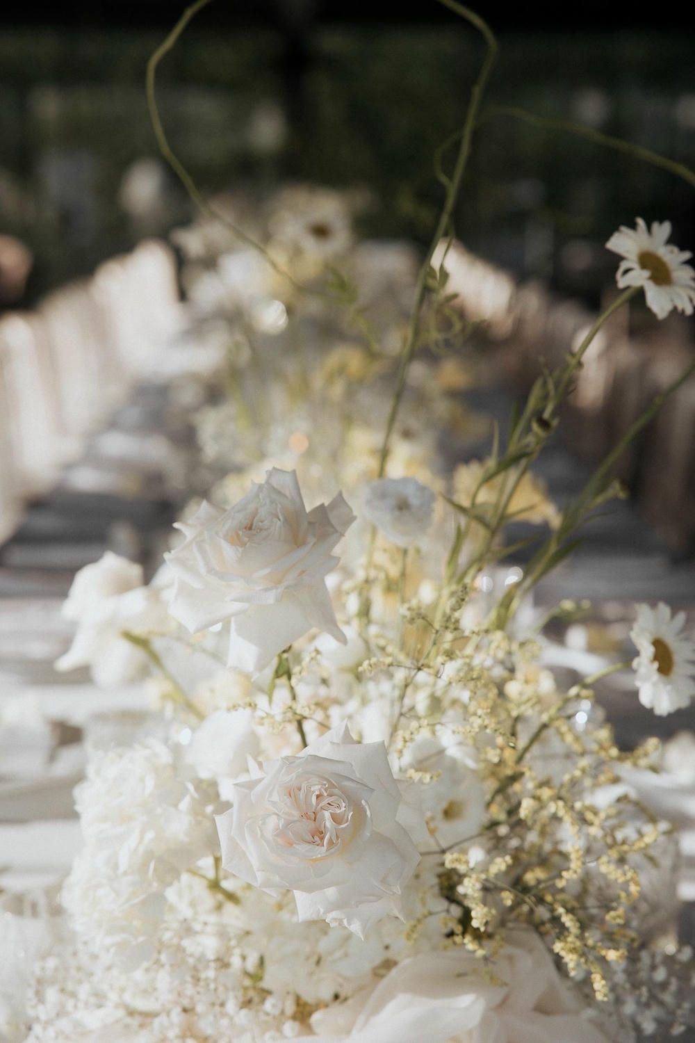 Elegant white floral arrangement featuring delicate blooms and baby's breath against a soft blurred background.