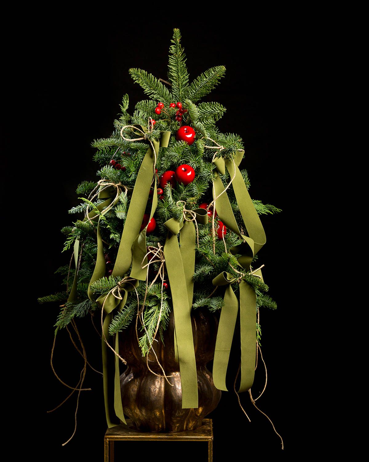 Festive holiday greenery with red berries and yellow ribbons displayed on a dark background.