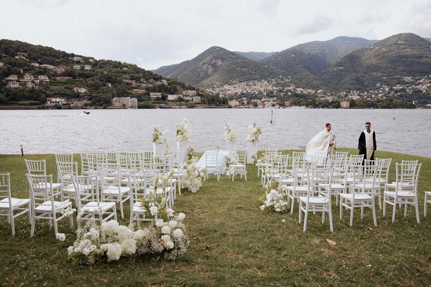 White chairs arranged for an outdoor wedding ceremony overlooking a scenic mountain lake landscape.