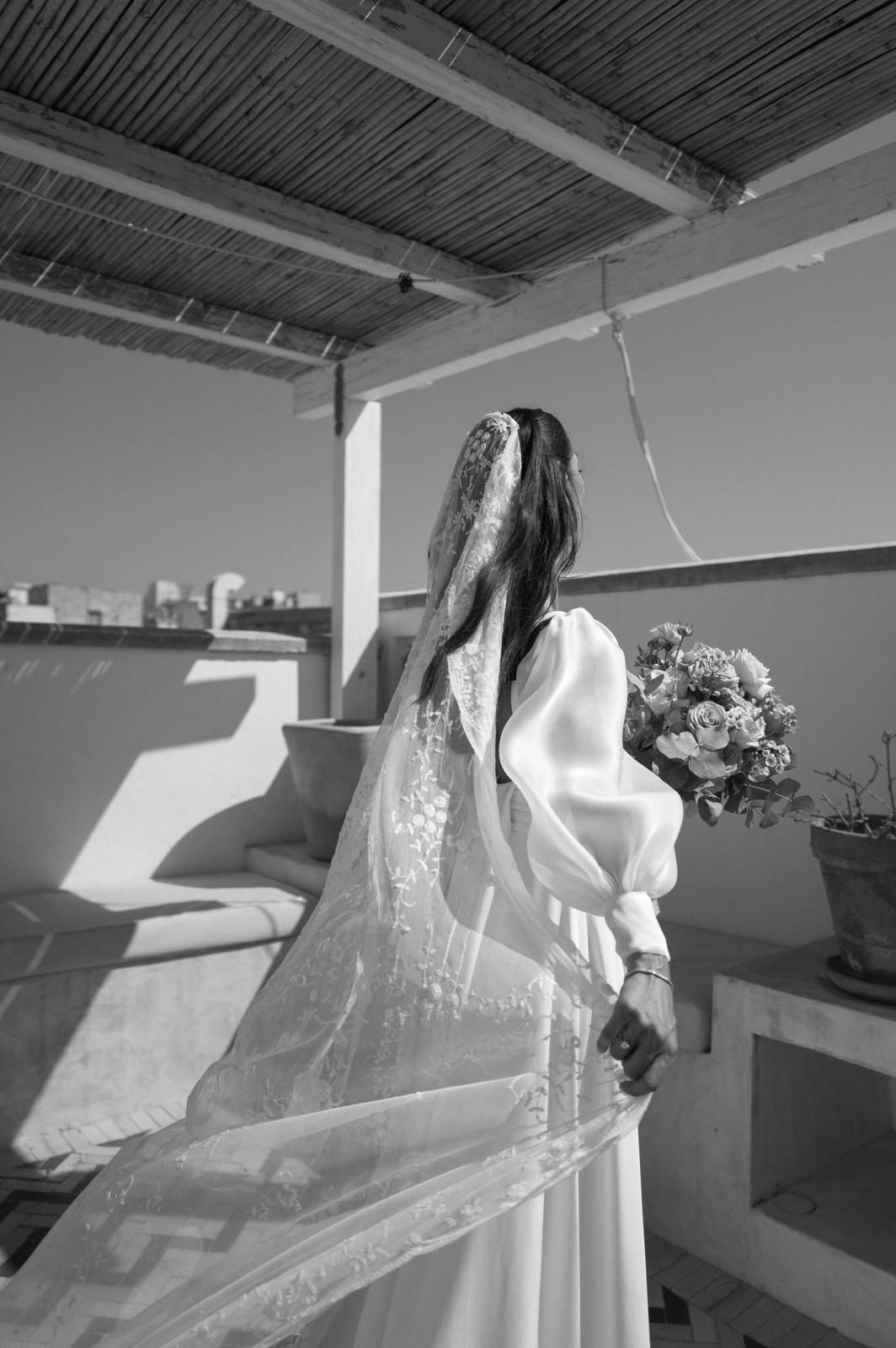 Artistic black and white bridal portrait showing flowing dress and veil in natural light.