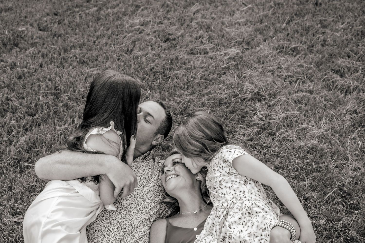 Black and white photo of family members embracing on grass.