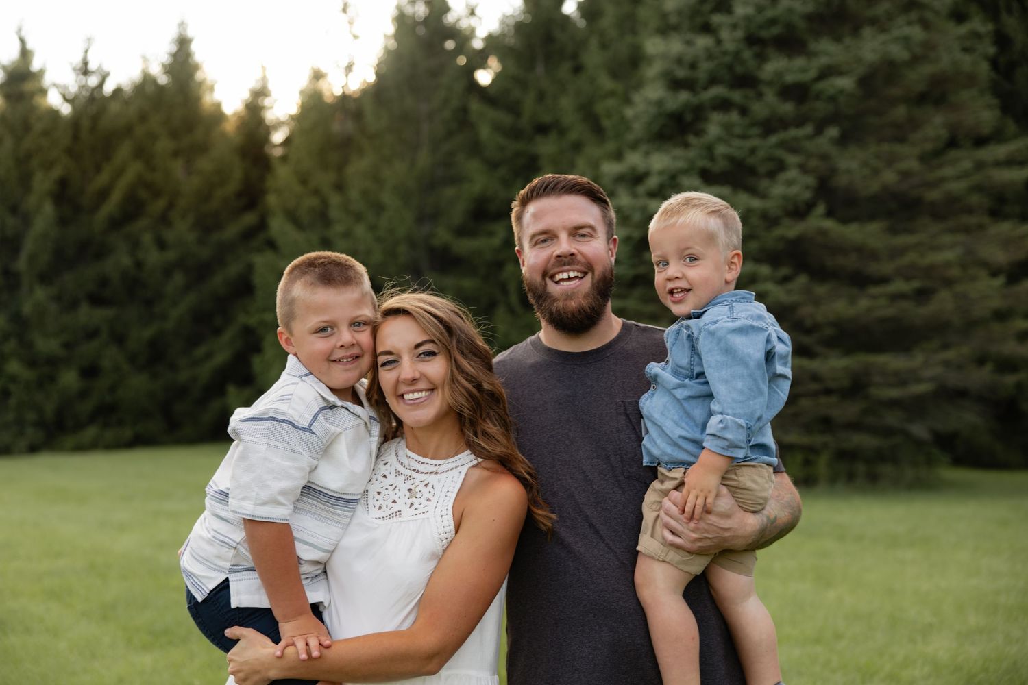Family portrait session outdoors with evergreen trees in background.
