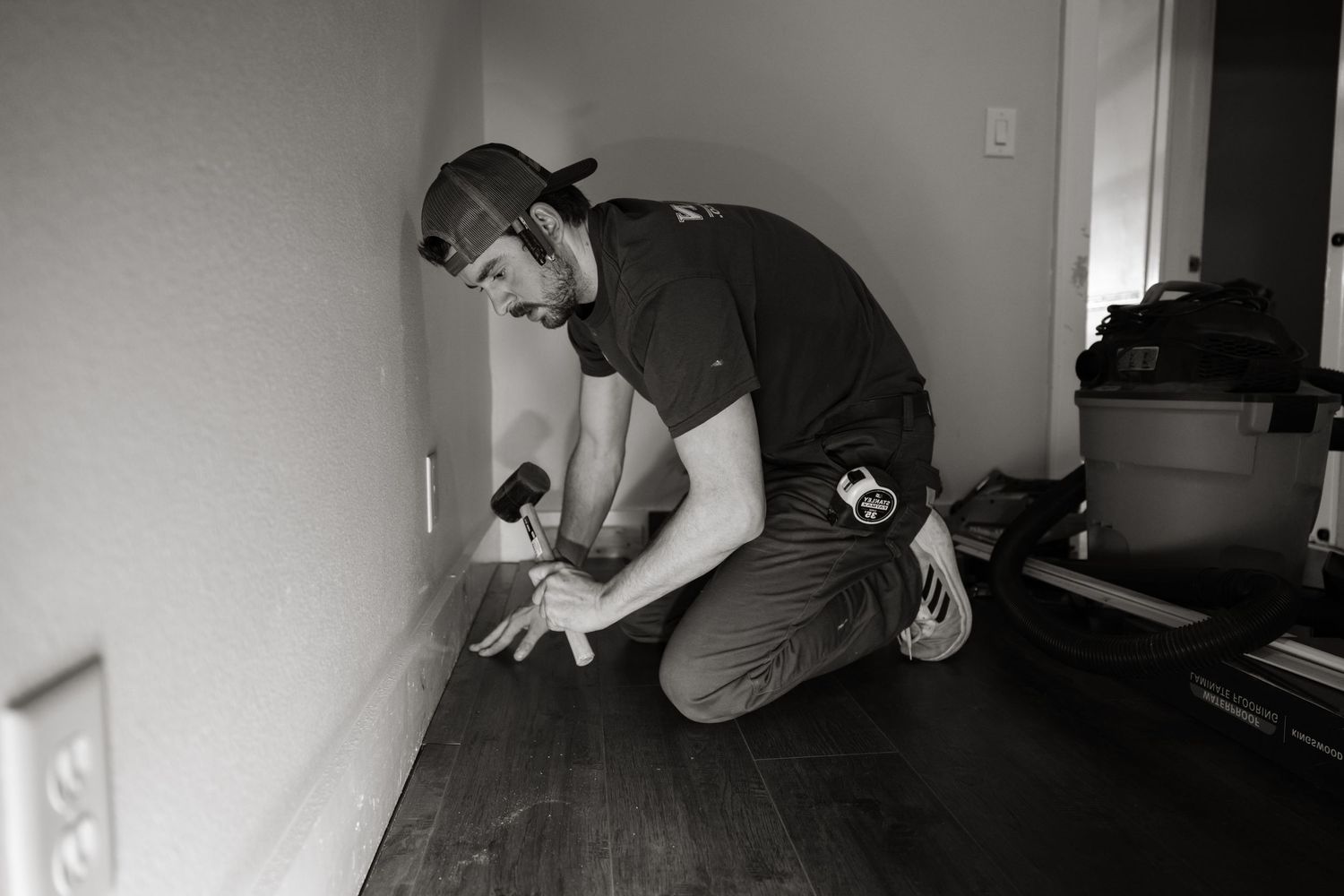 Black and white photo of someone working on home improvement project indoors.