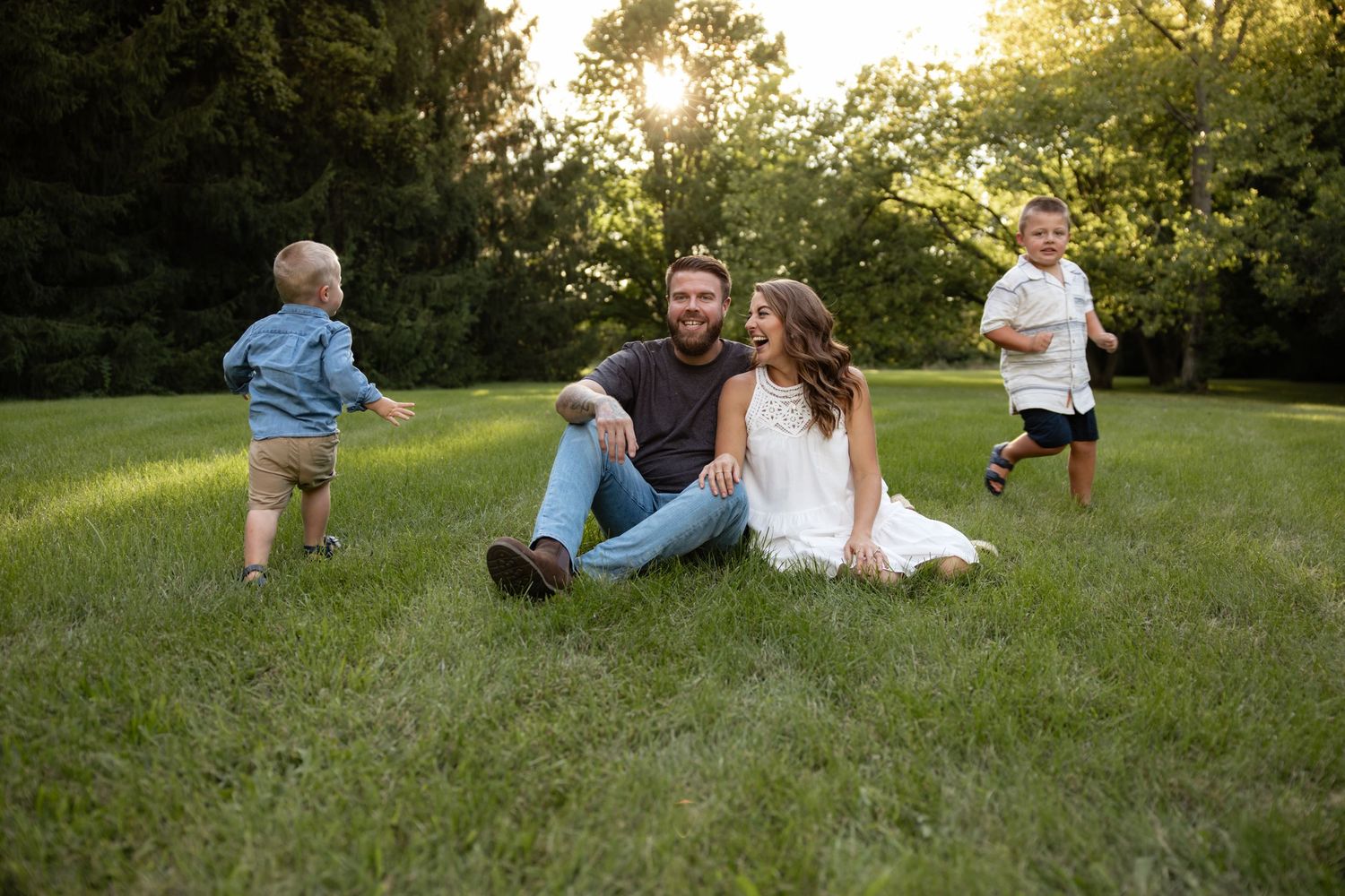 Family members spread out on grassy hill during sunset photoshoot.