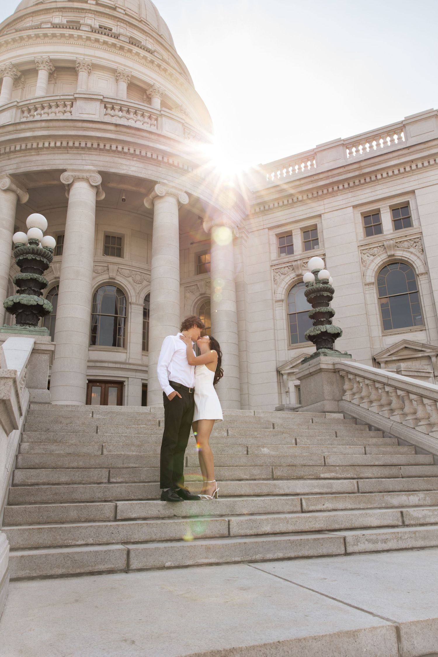 Romantic couple on grand marble steps of capitol building at sunset.