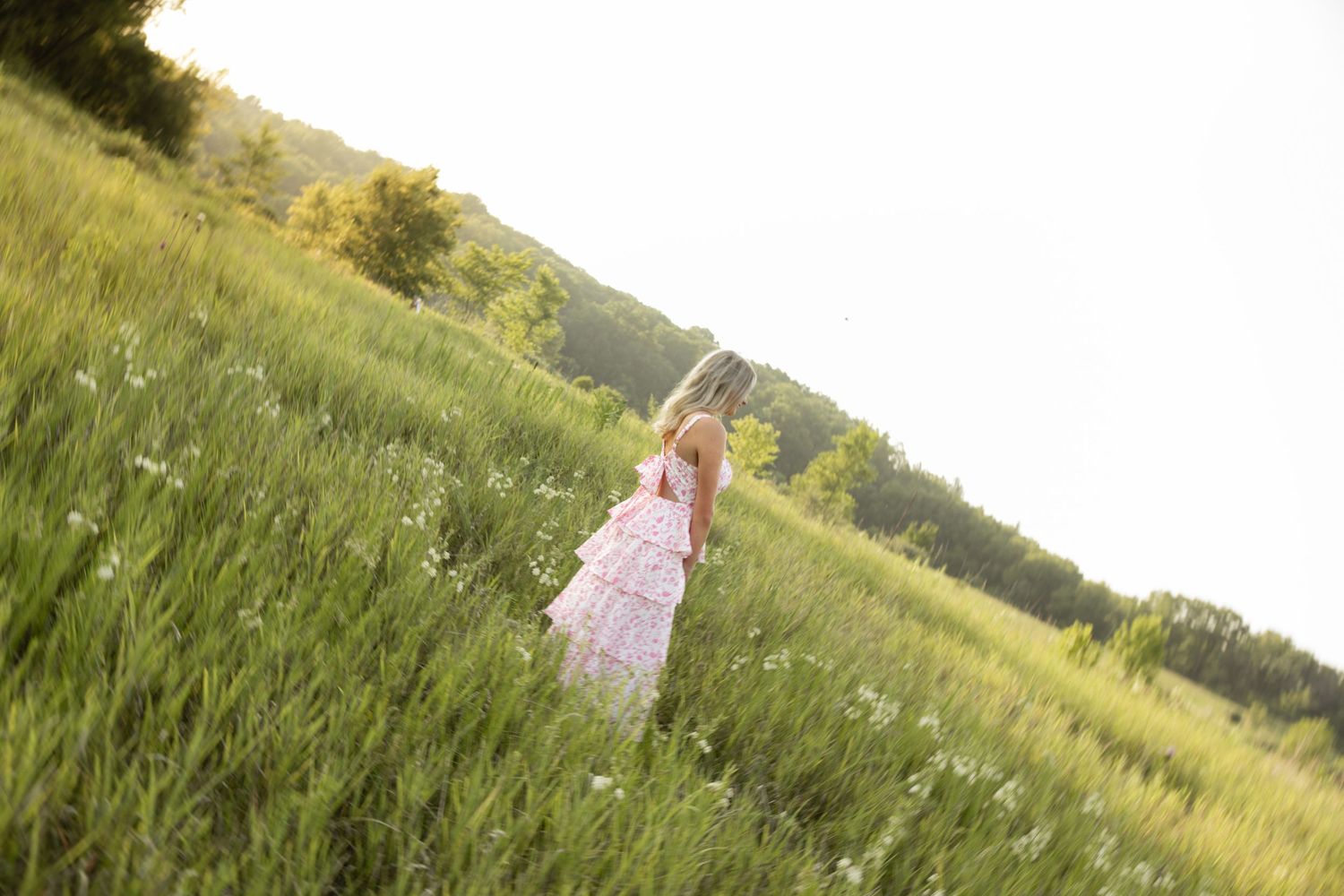 Candid lifestyle photoshoot in a sunny meadow with tall grass and wildflowers at golden hour.