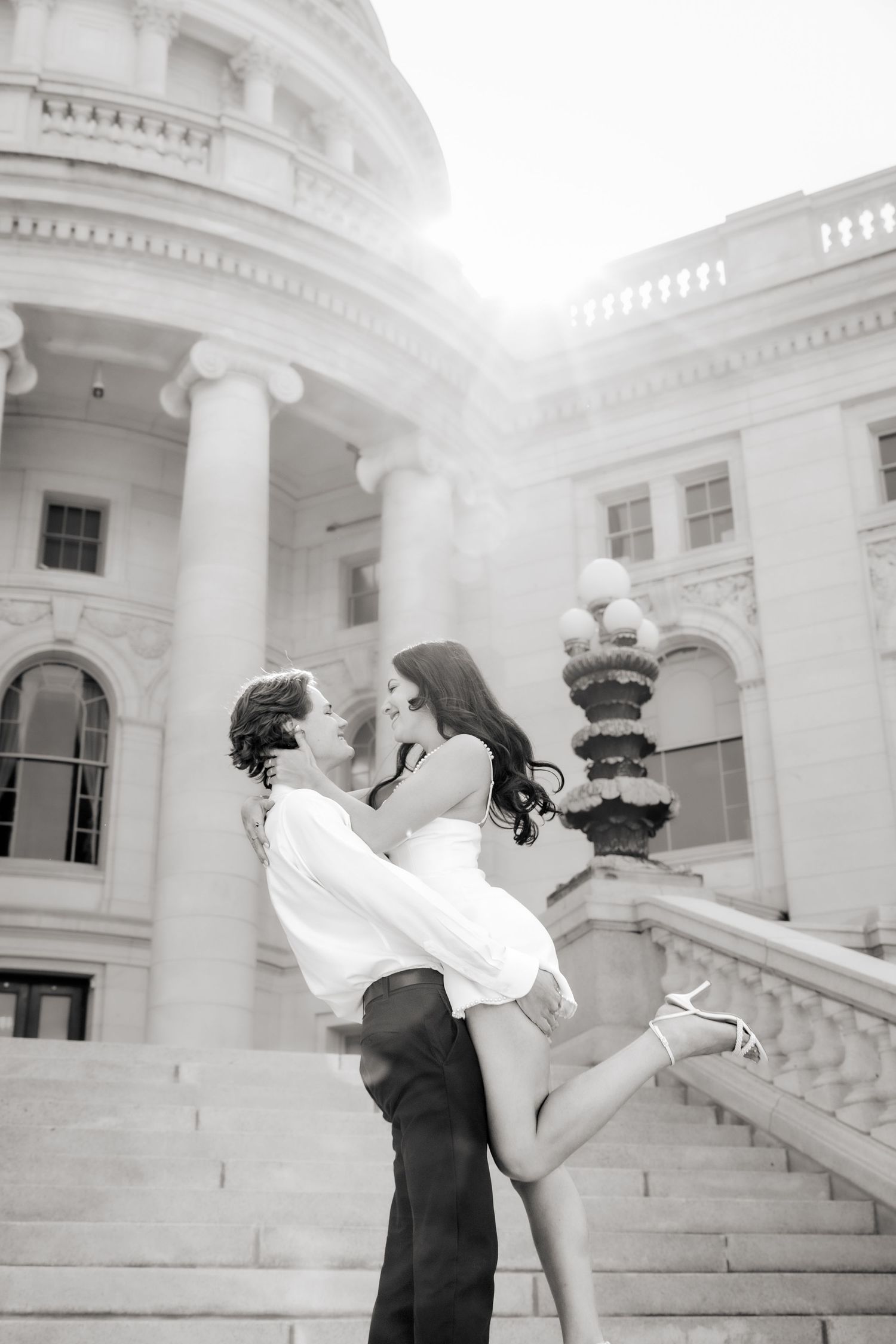 Artistic black and white engagement photos captured on elegant white stone steps.