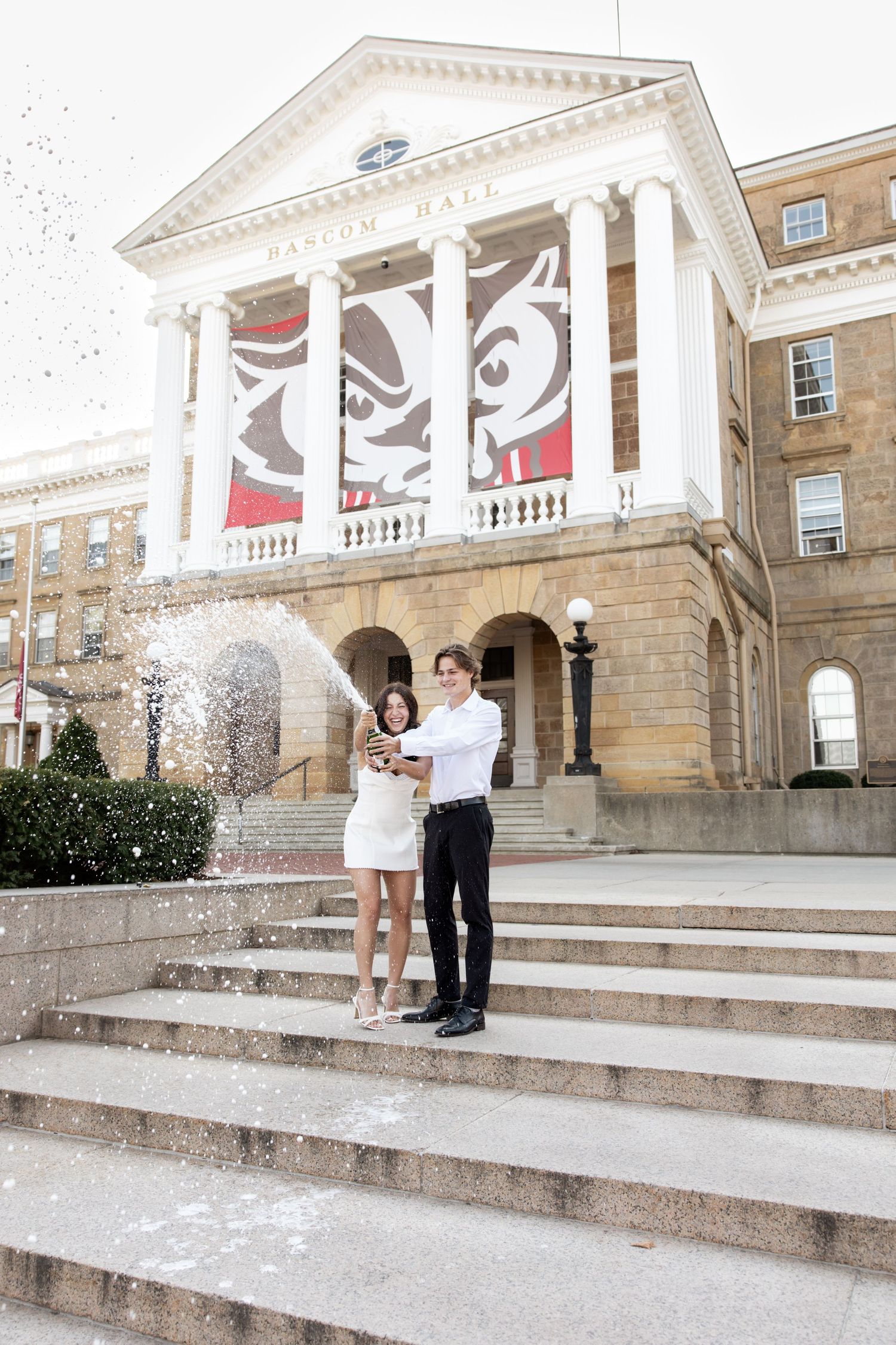 Graduation photos taken on grand stone steps of a historic university building with white columns.