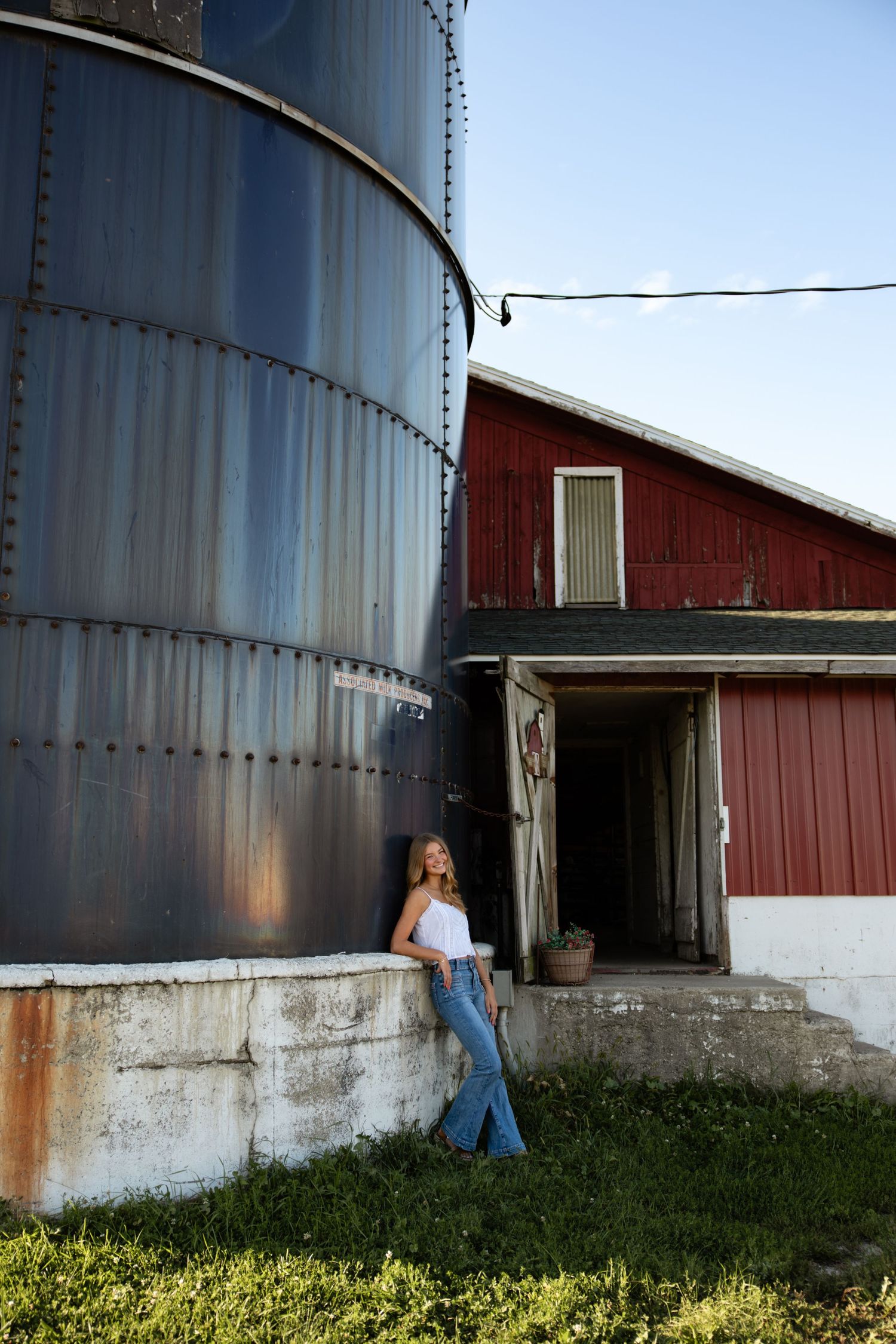Rural farm photography with metal grain silo and red barn backdrop in afternoon light.