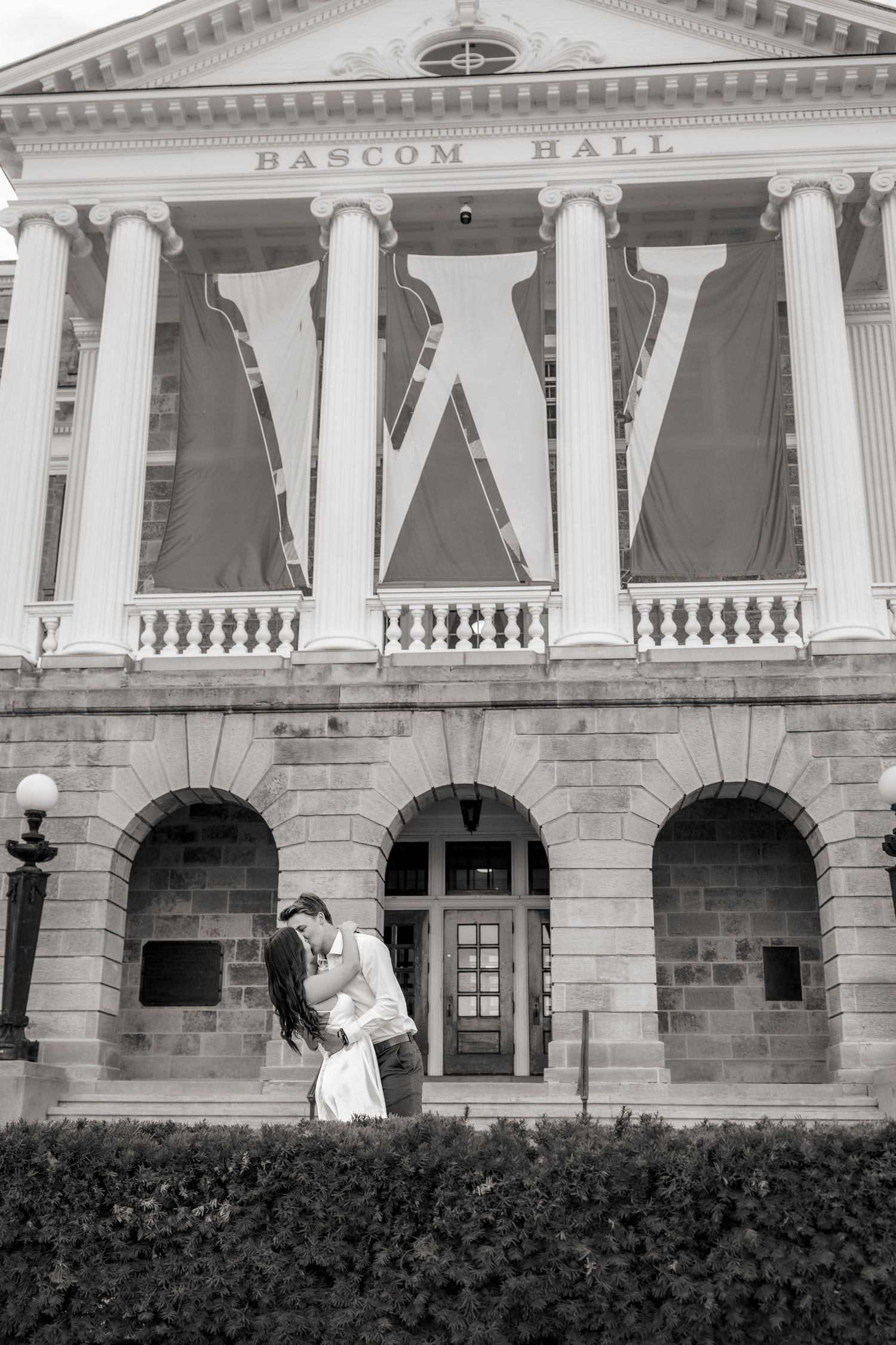 A romantic moment captured in black and white outside a historic building with classical columns.