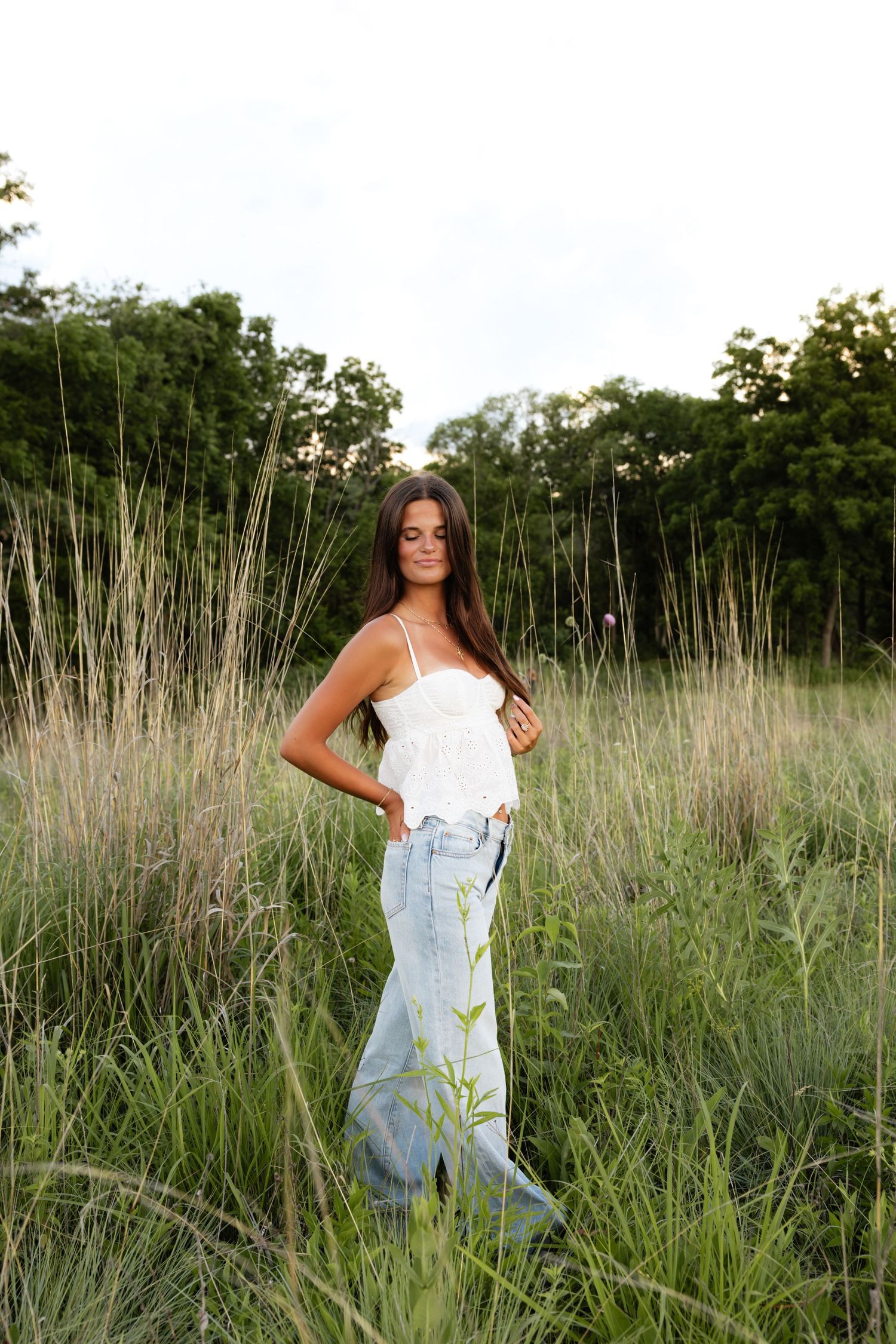 Portrait session in tall prairie grass wearing white top and denim.