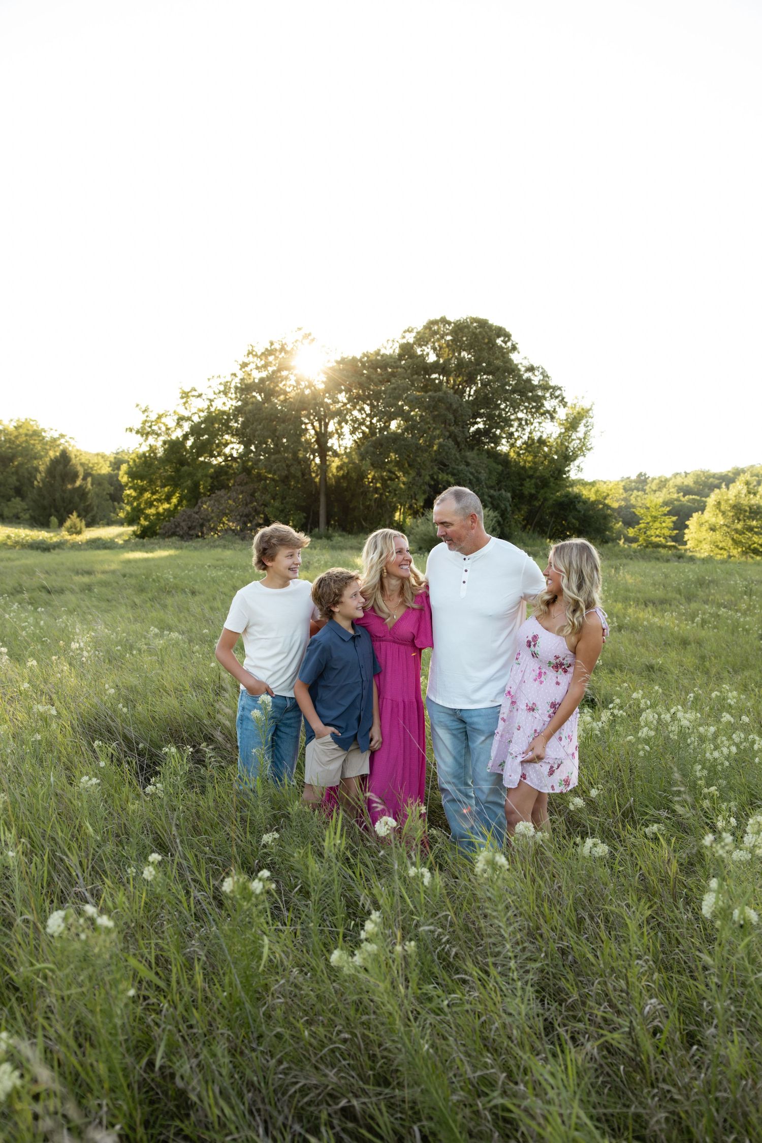 Family members gather in a wildflower meadow during sunset for a casual portrait session.