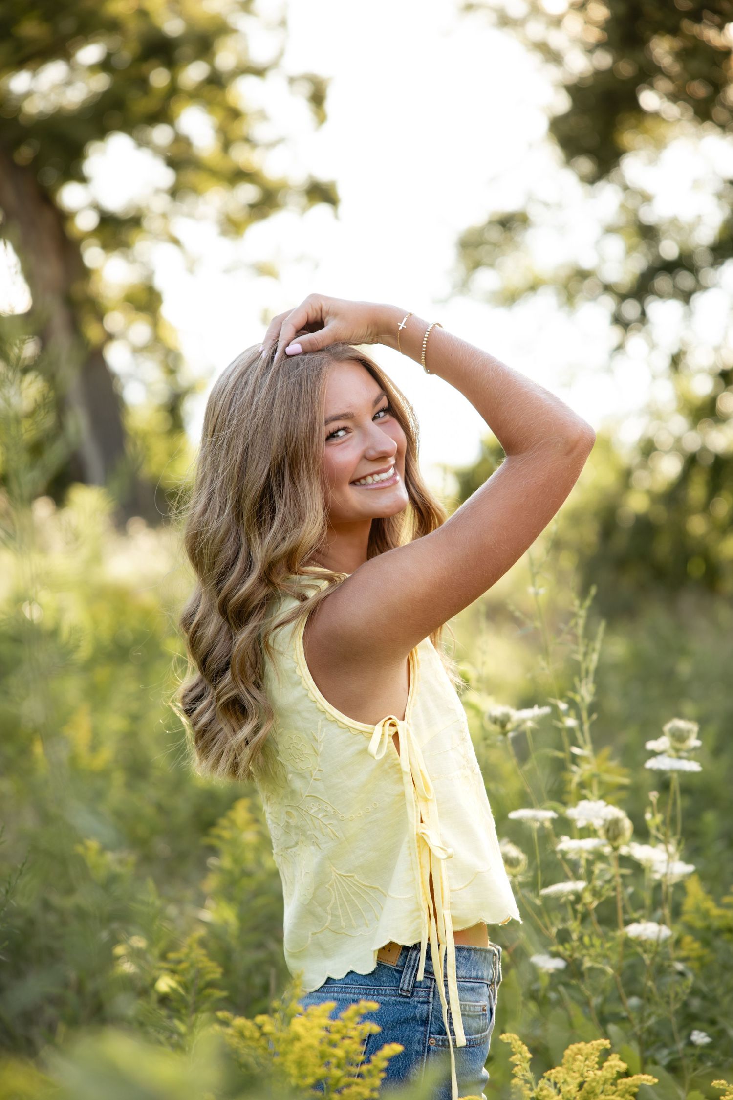 Summer fashion shoot featuring a yellow top and denim shorts in a wildflower field at sunset.