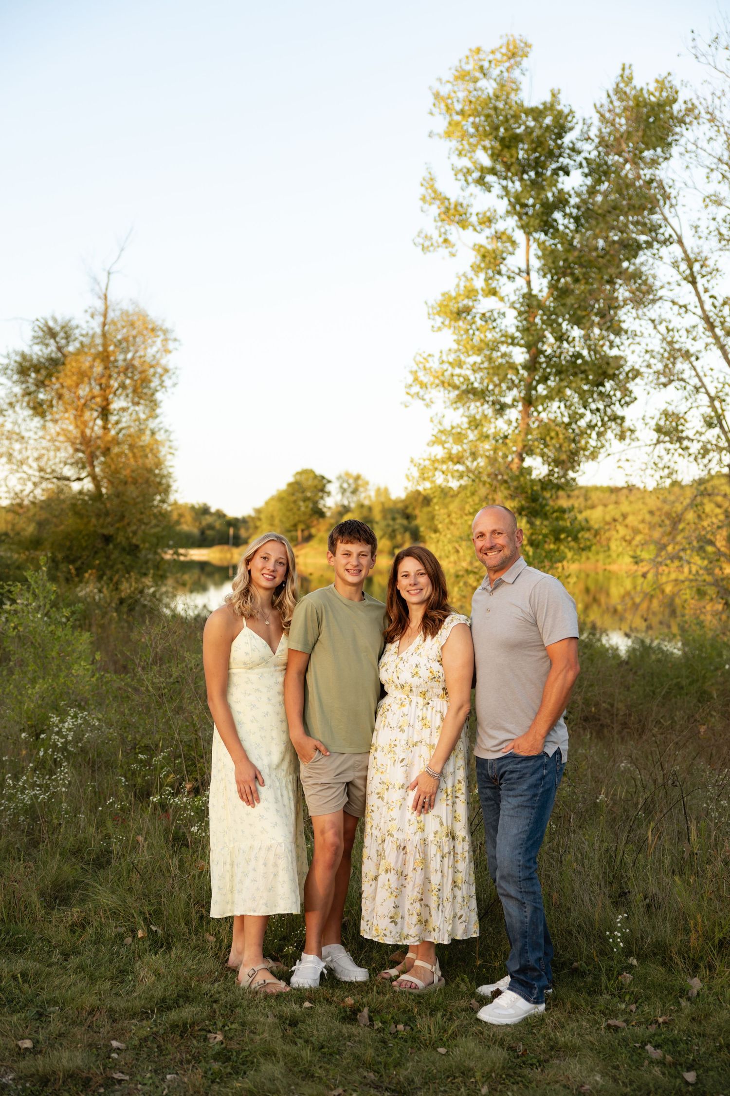 Family of four posing together in a natural outdoor setting during golden hour.