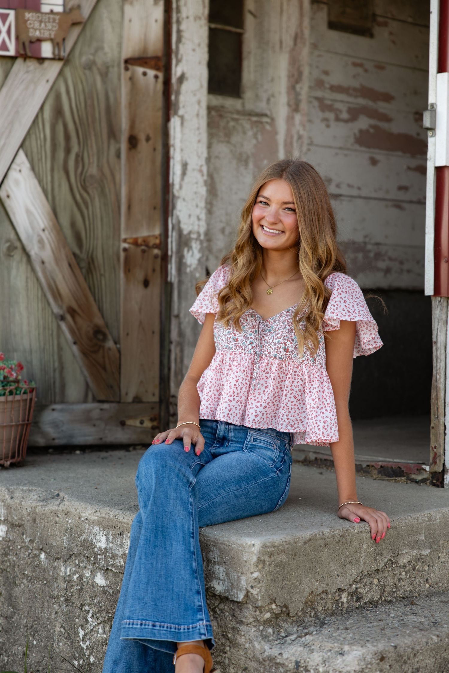 Vintage-inspired portraits against distressed barn walls featuring floral top and classic jeans.
