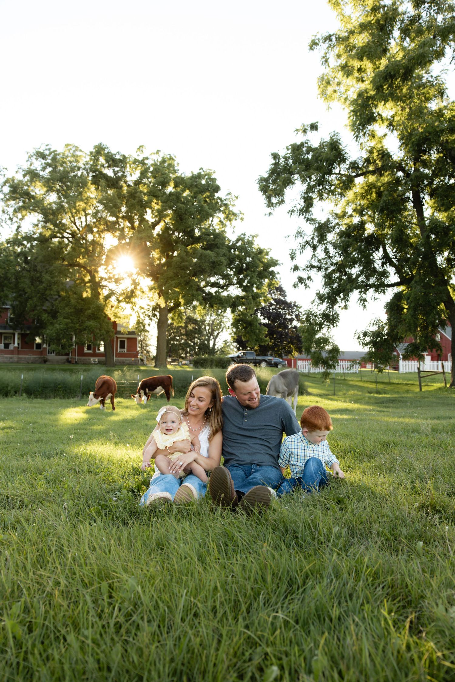 Family enjoying outdoor time together on grassy hillside at sunset.