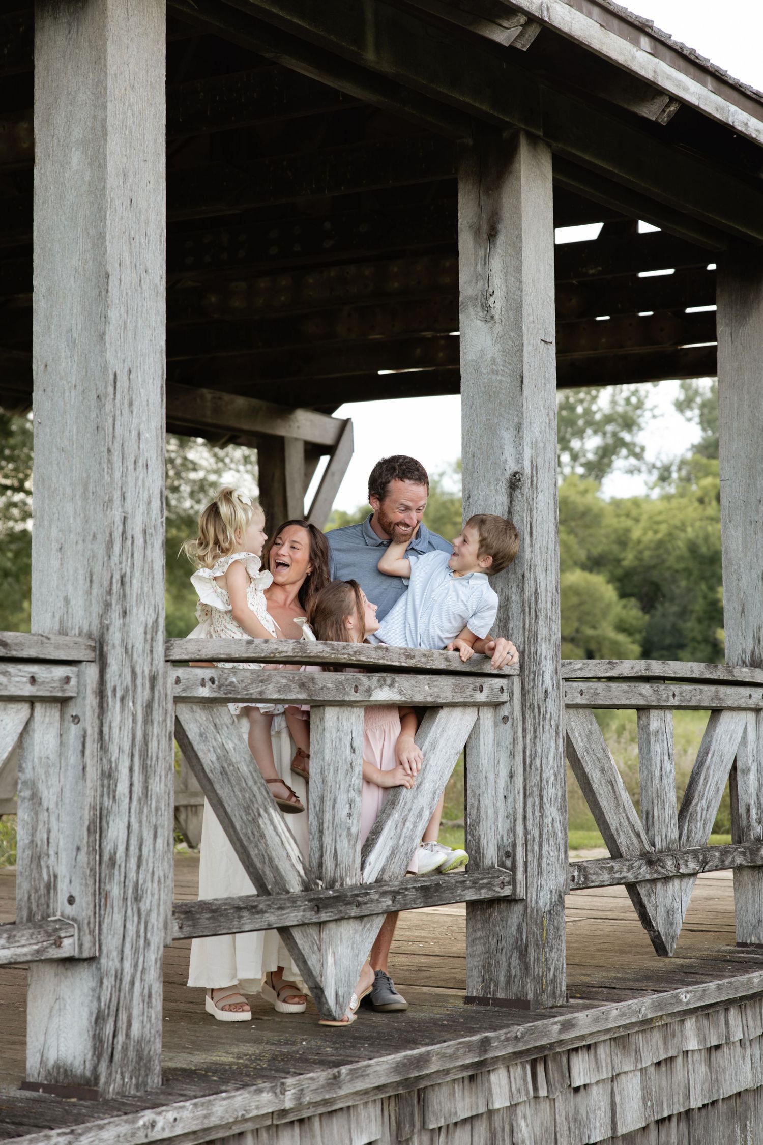 Candid family moment on a rustic wooden bridge deck during a photo session.