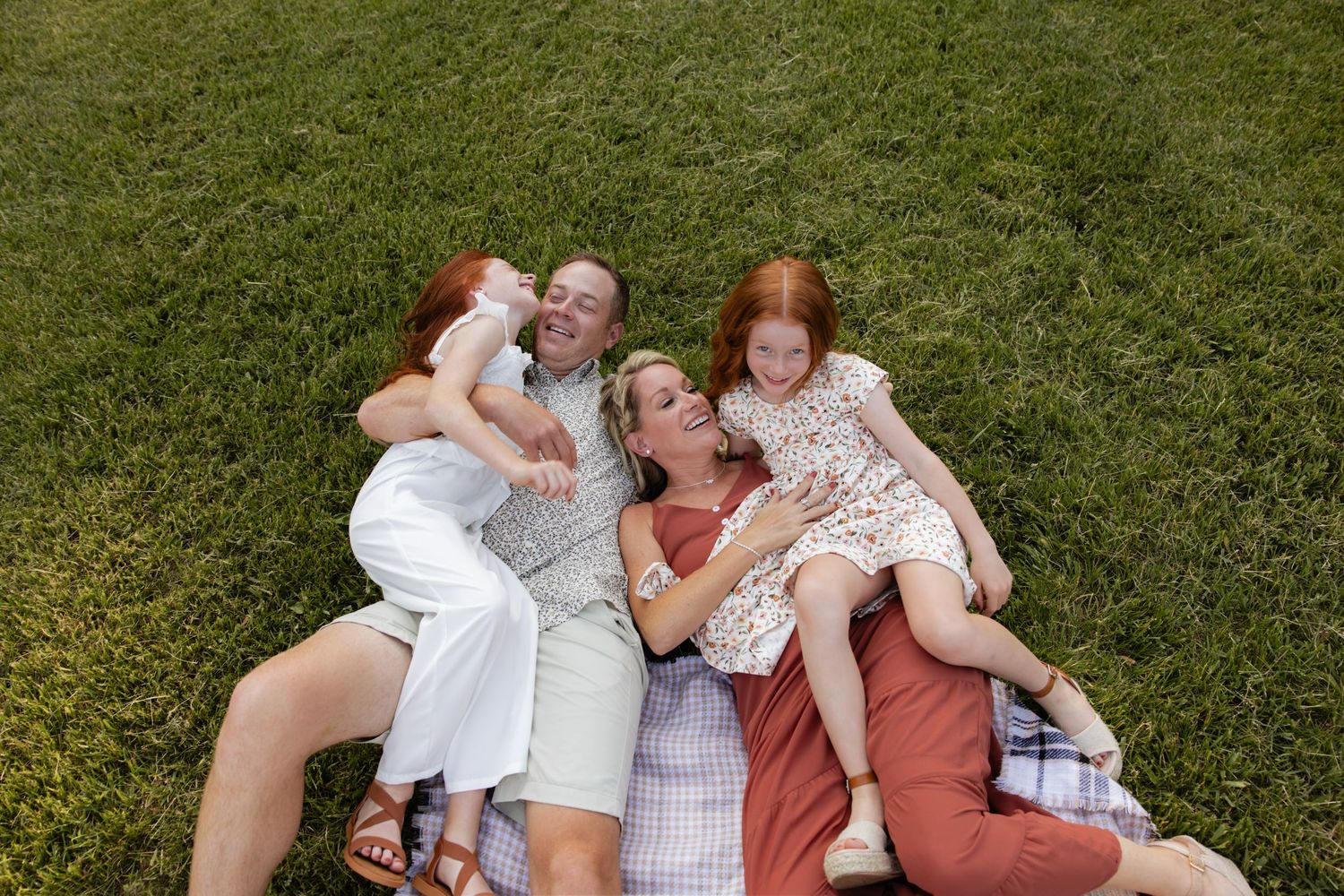 Family lying together on green grass during outdoor photo session.