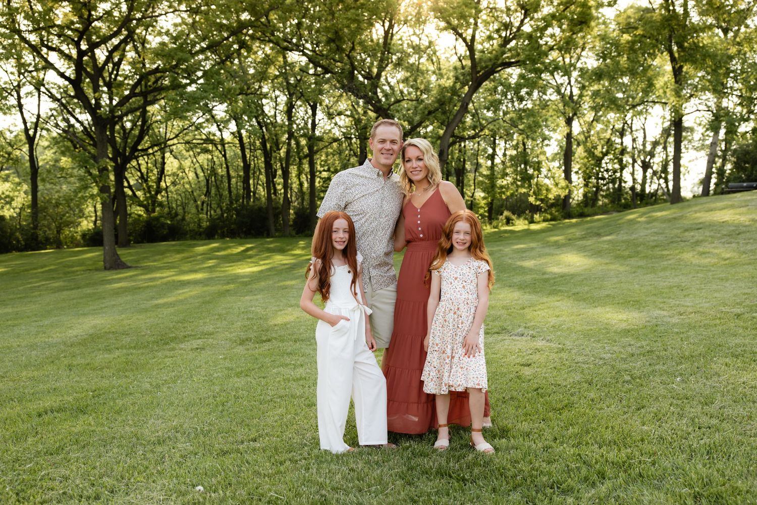 Candid family moment captured in a sunlit grassy field.