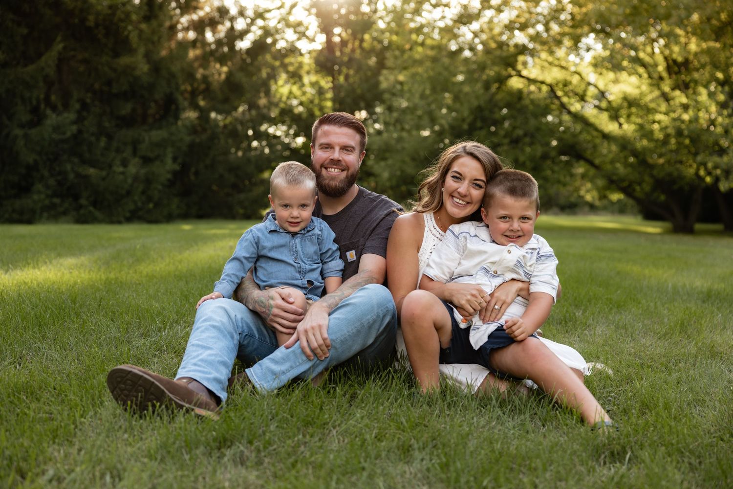 Family group relaxing together on grass during summer photo session.