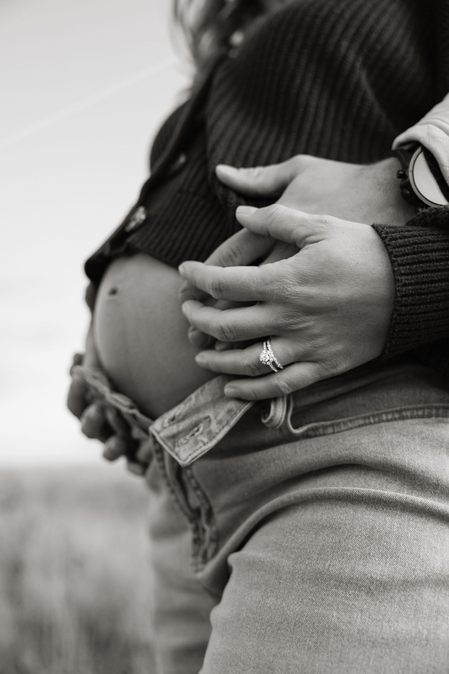Close-up black and white shots of hands cradling pregnant belly.