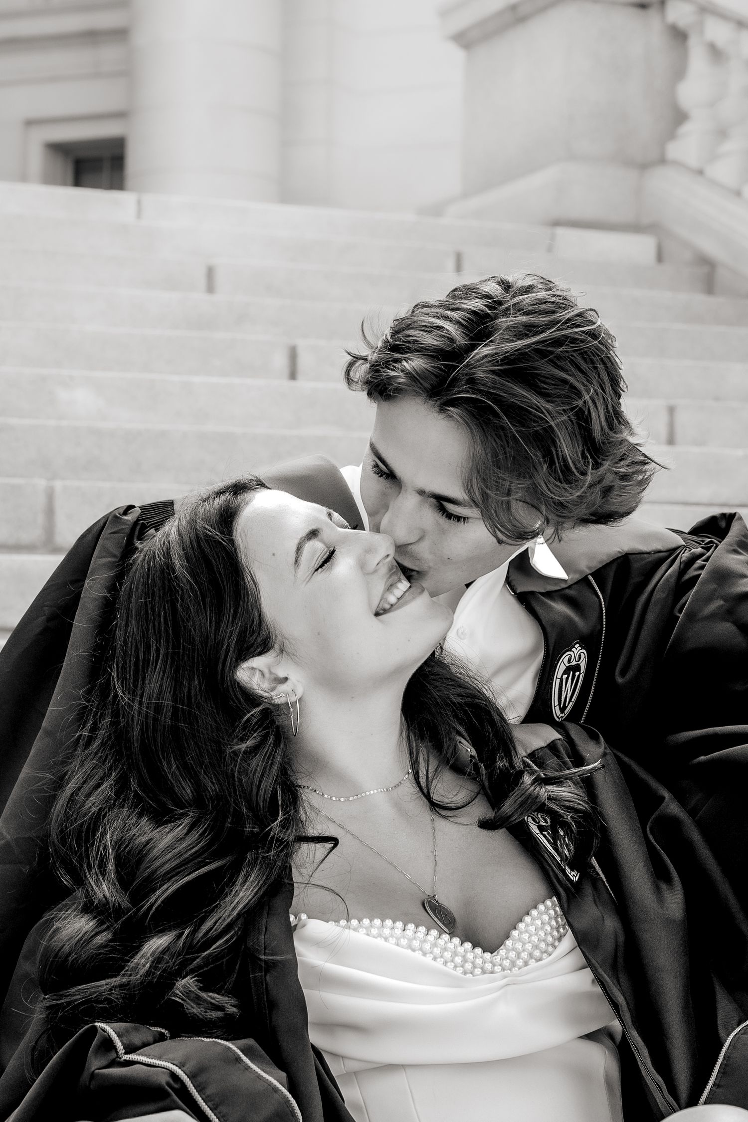 Black and white romantic kiss portrait in front of architectural columns.