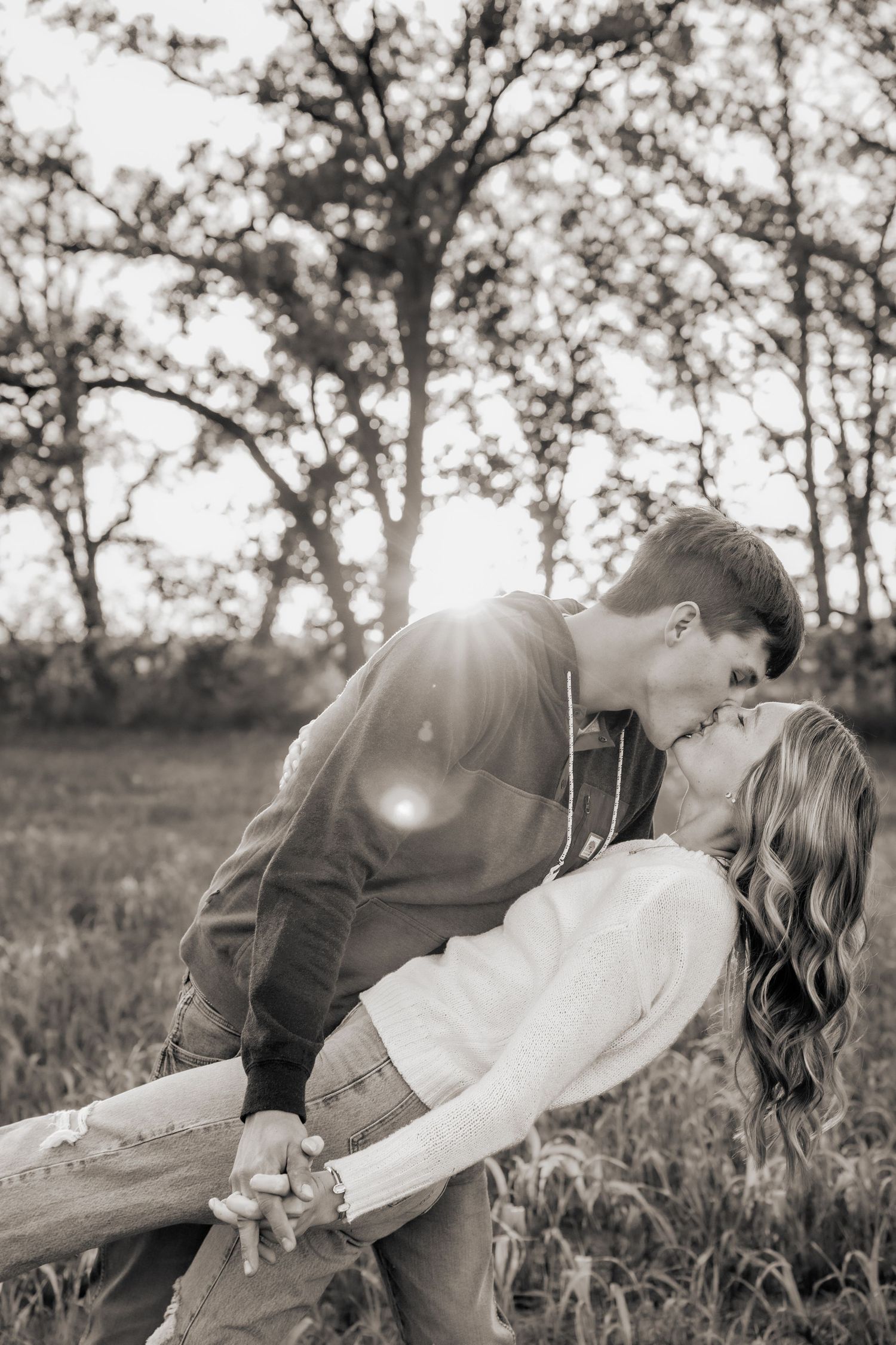 A romantic moment captured in black and white as a couple shares a tender kiss in nature.