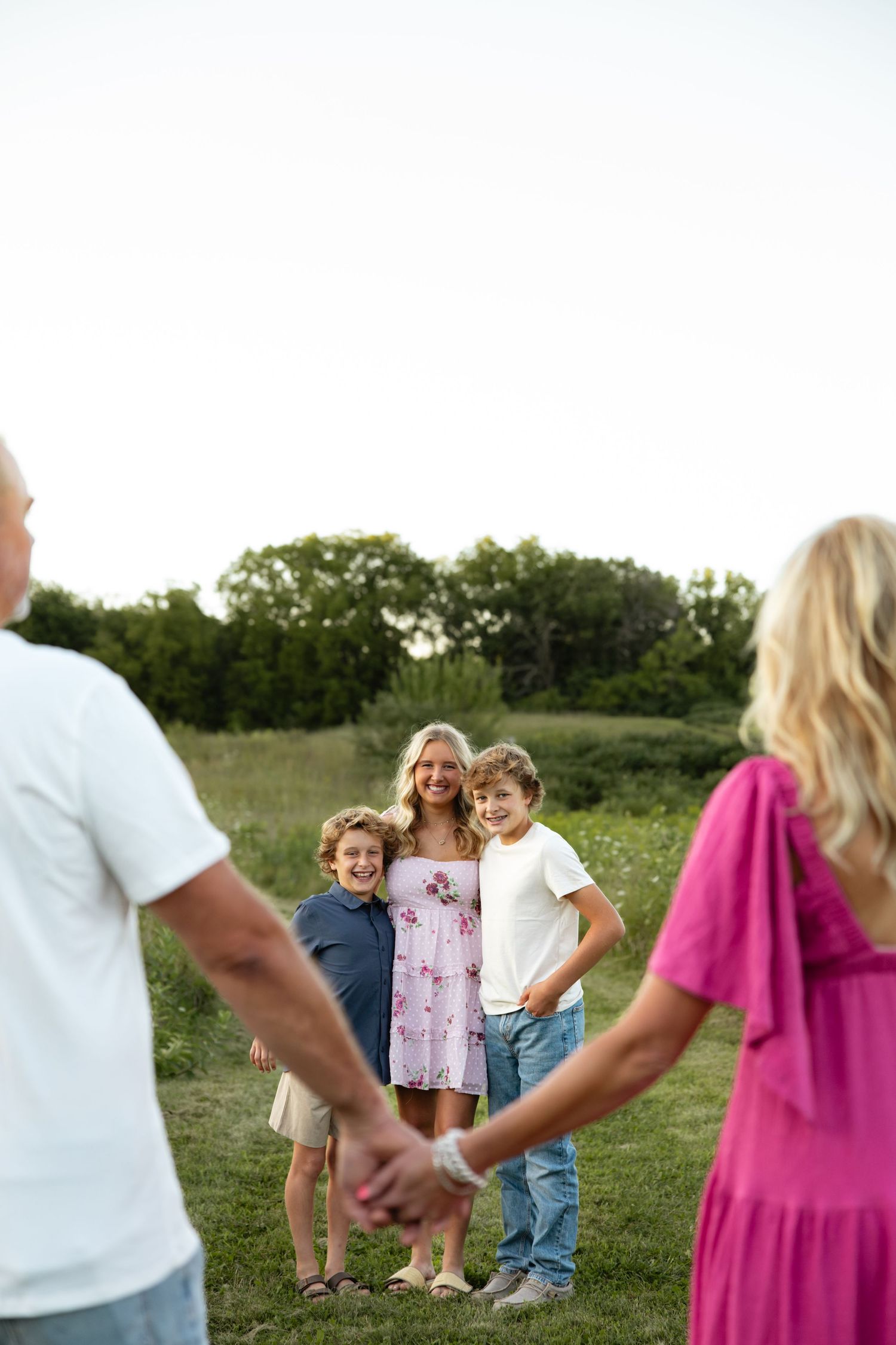 Family enjoying a playful moment together in a grassy field during golden hour.