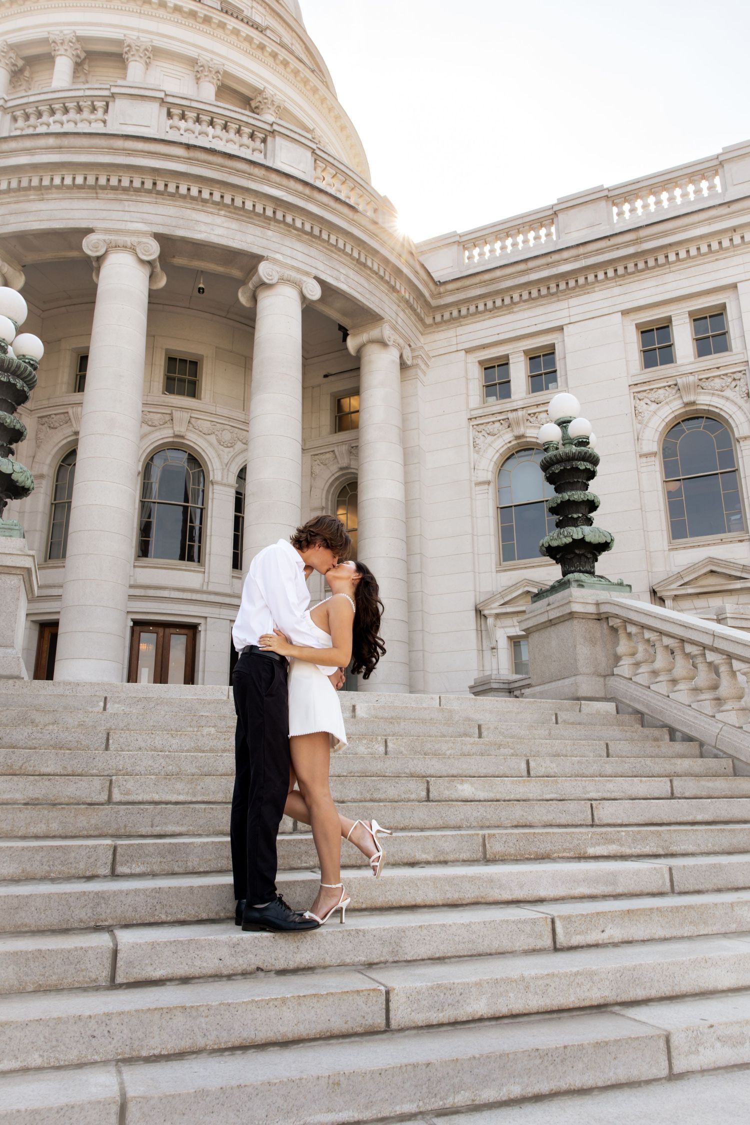 Couple poses for engagement photos on the sweeping steps of a historic building.