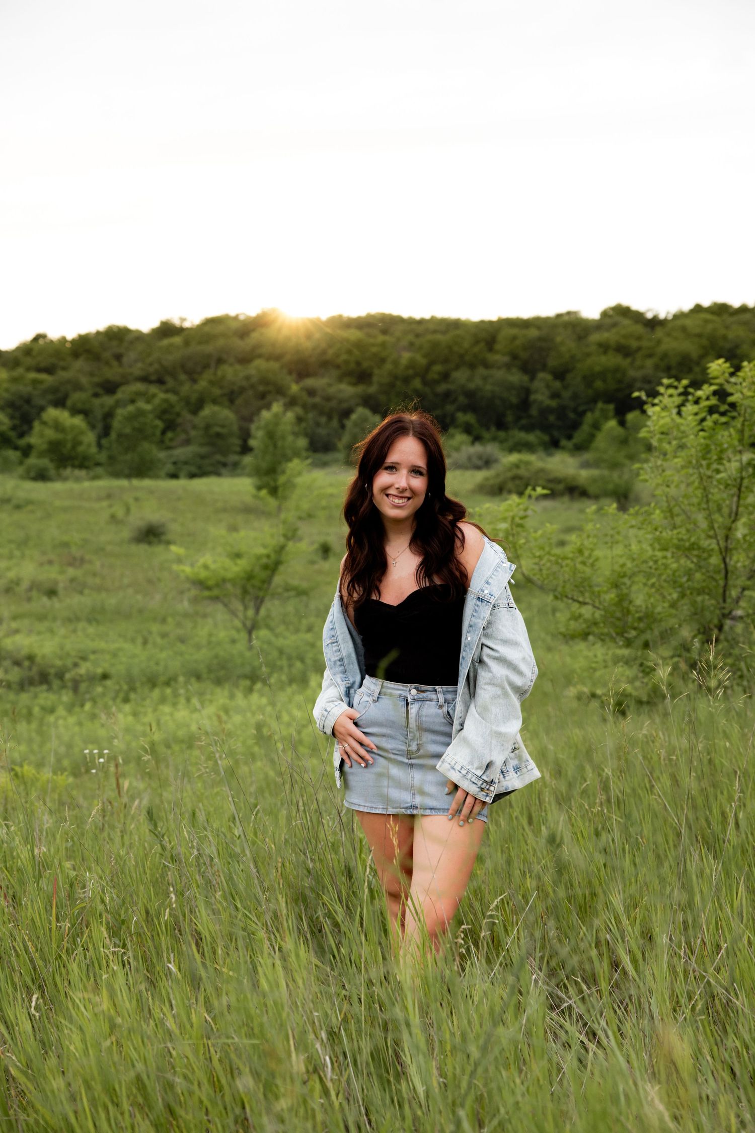 Outdoor portrait session in tall grass featuring denim and casual wear against natural scenery.