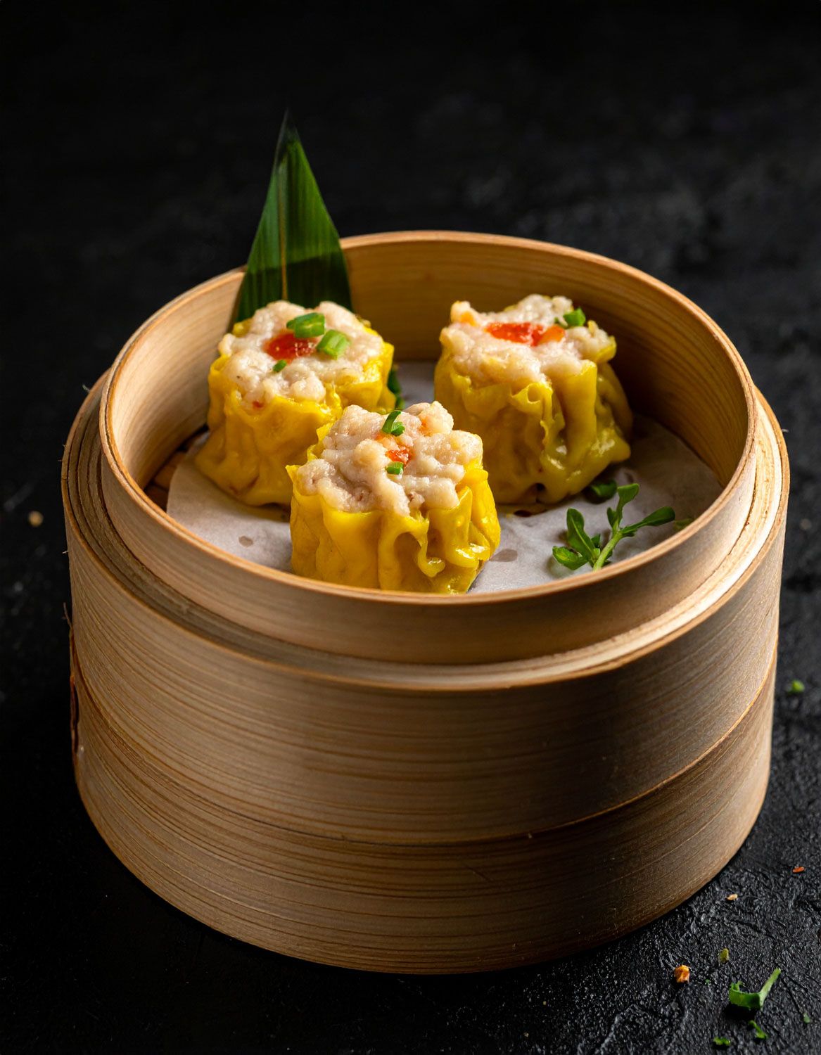 Ravioli dim sum al vapore serviti nel tradizionale cestino di bambù con guarnizioni.