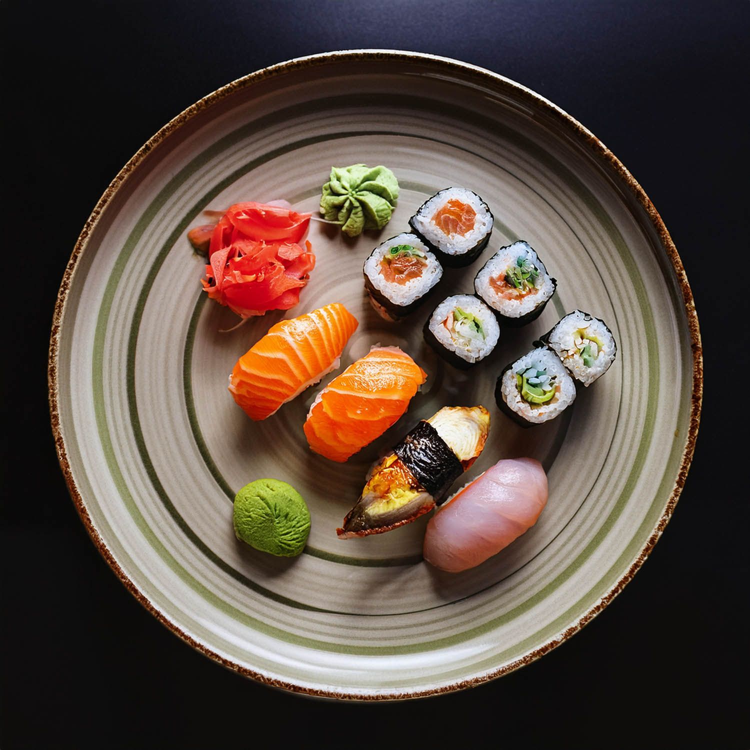 Pezzi di sushi assortiti, inclusi nigiri al salmone e maki, impiattati ad arte su piatti di ceramica.