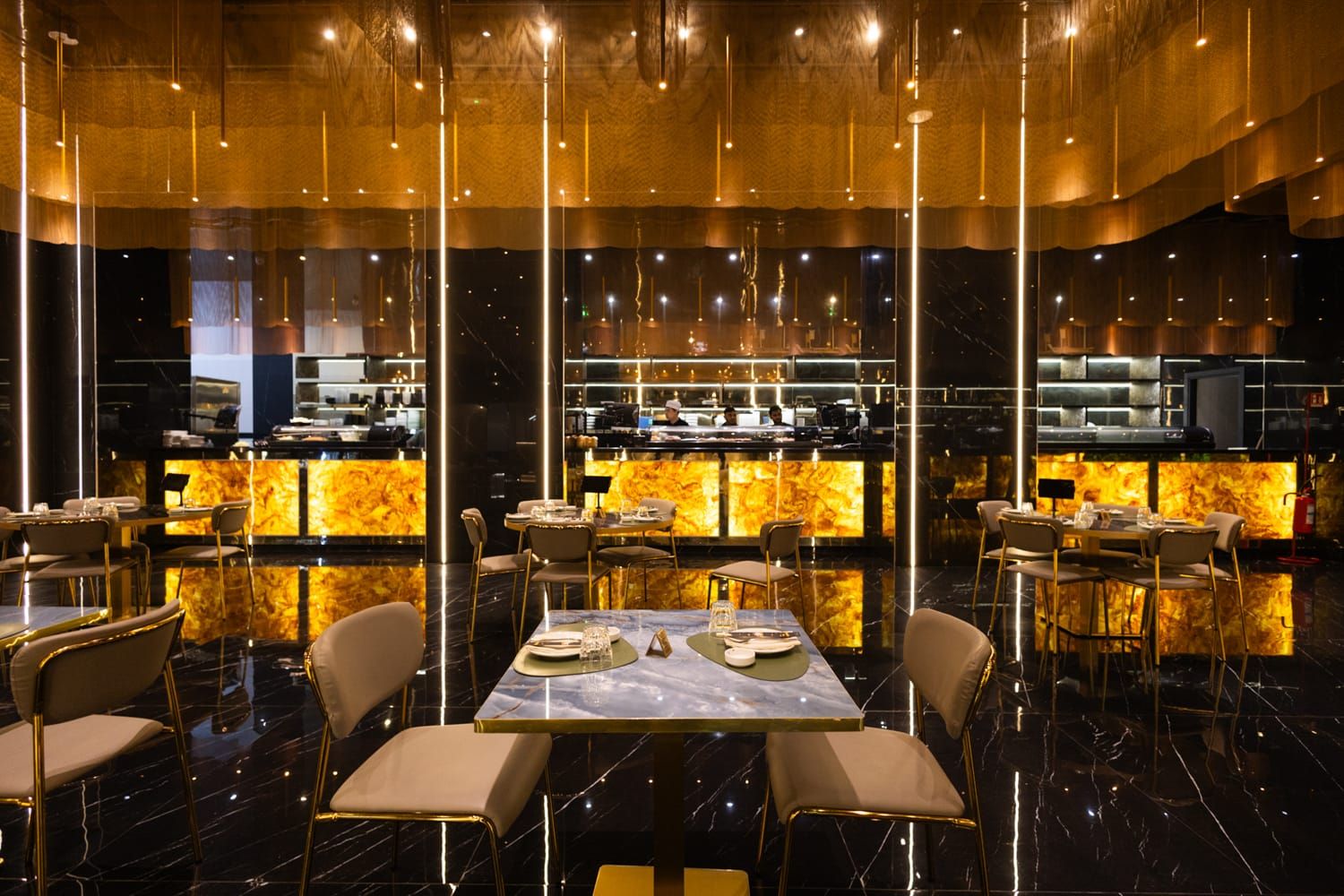 L'interno della sala di Roku Sushi Restaurant con luci calde e tavoli moderni della sala principale a Trapani.