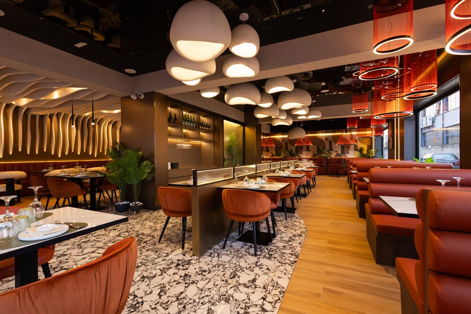 Sala di Roku Sushi Restaurant con luci calde, pavimenti in legno e divanetti in pelle a Barcellona Pozzo di Gotto in Sicilia.