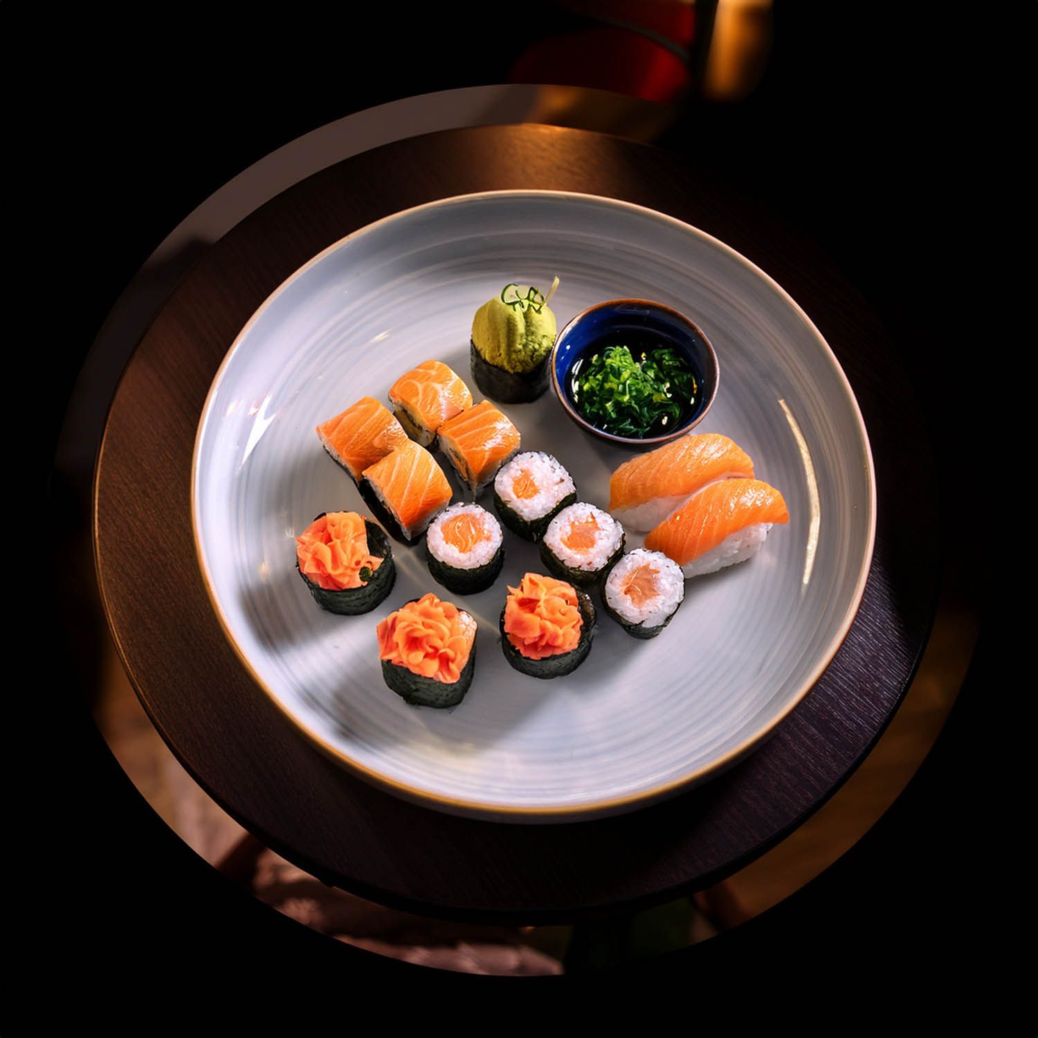 Presentazione minimalista di pezzi di sushi su piatti grigi contro uno sfondo scuro.