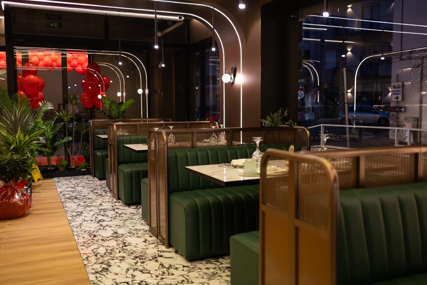 Sala di Roku Sushi Restaurant con divanetti in velluto verde e lampade in ottone curvato in Sicilia a Barcellona Pozzo di Gotto.