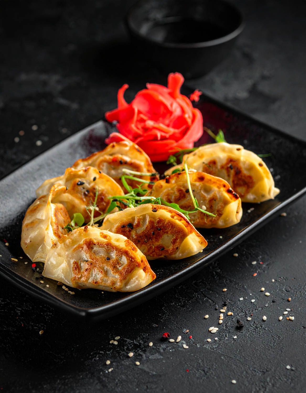 Gyoza decorati serviti su un piatto nero al ristorante sushi Roku.