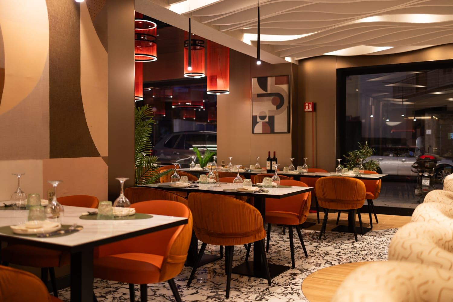 Interni di Roku Sushi Restaurant con sedie arancioni ed eleganti tavoli apparecchiati a Barcellona Pozzo di Gotto in Sicilia.
