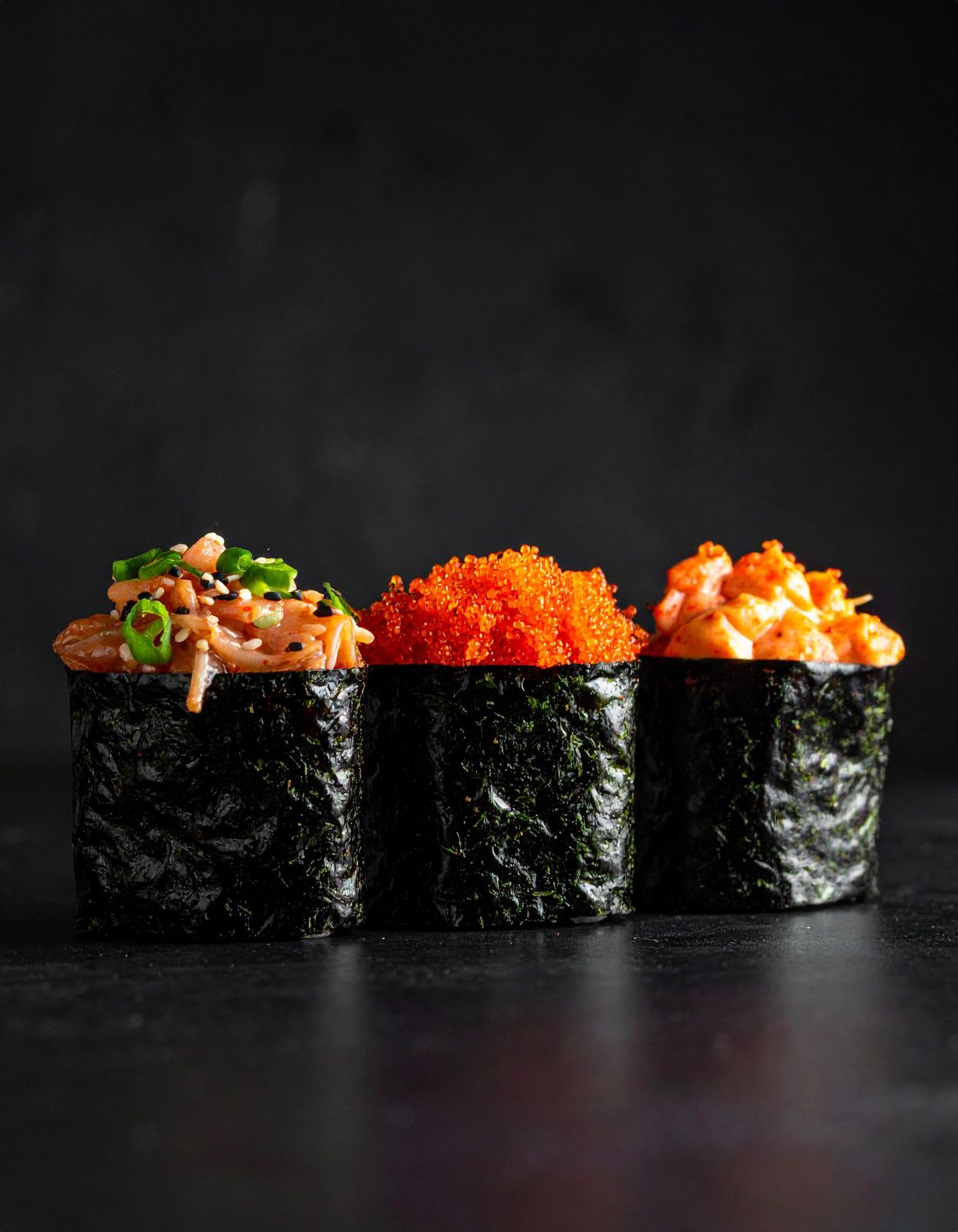 Primo piano di maki guarniti con uova di pesce e decorazioni su sfondo scuro.
