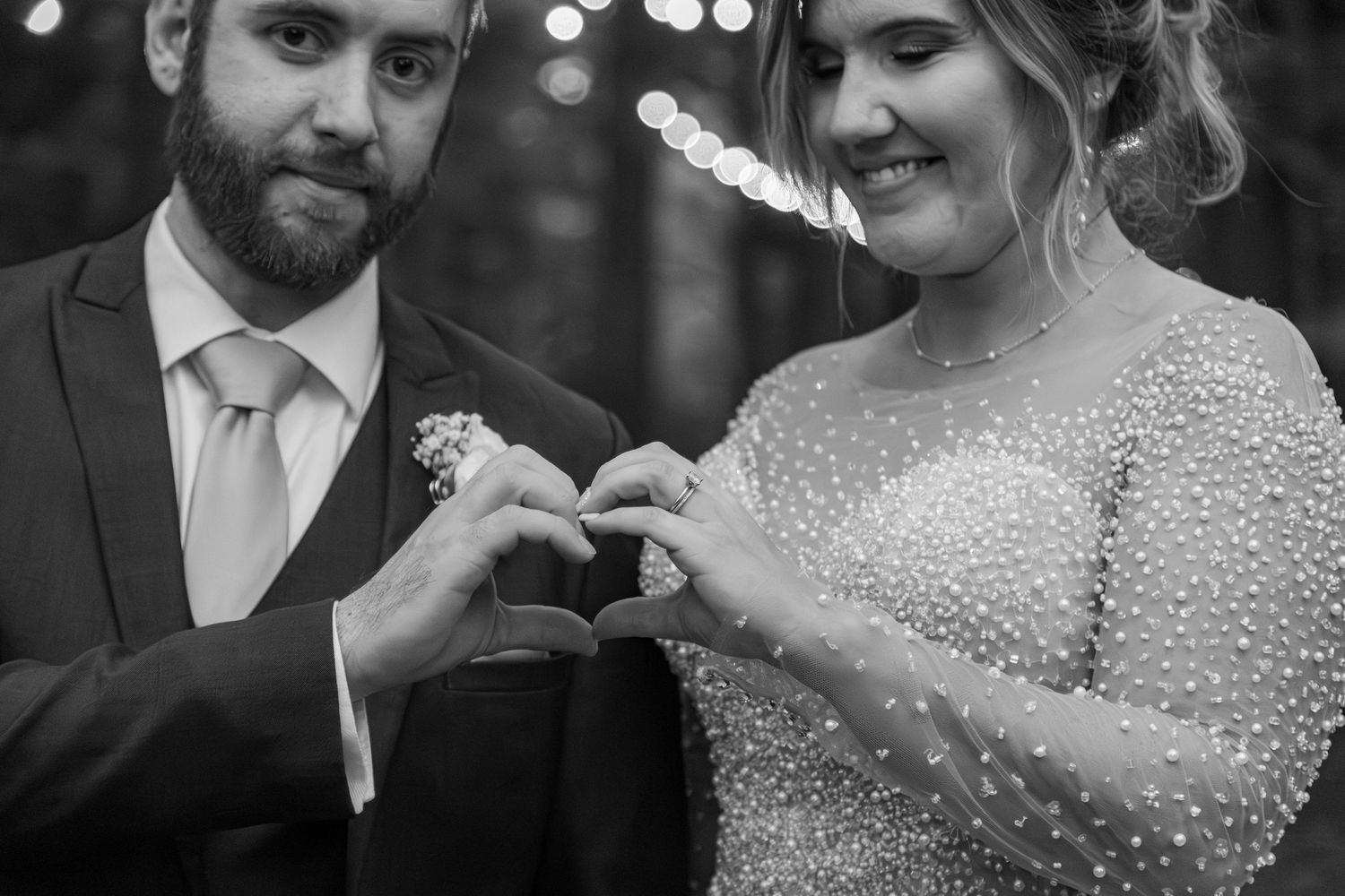 A couple shares an intimate moment at a wedding celebration with glittering lights in the background.