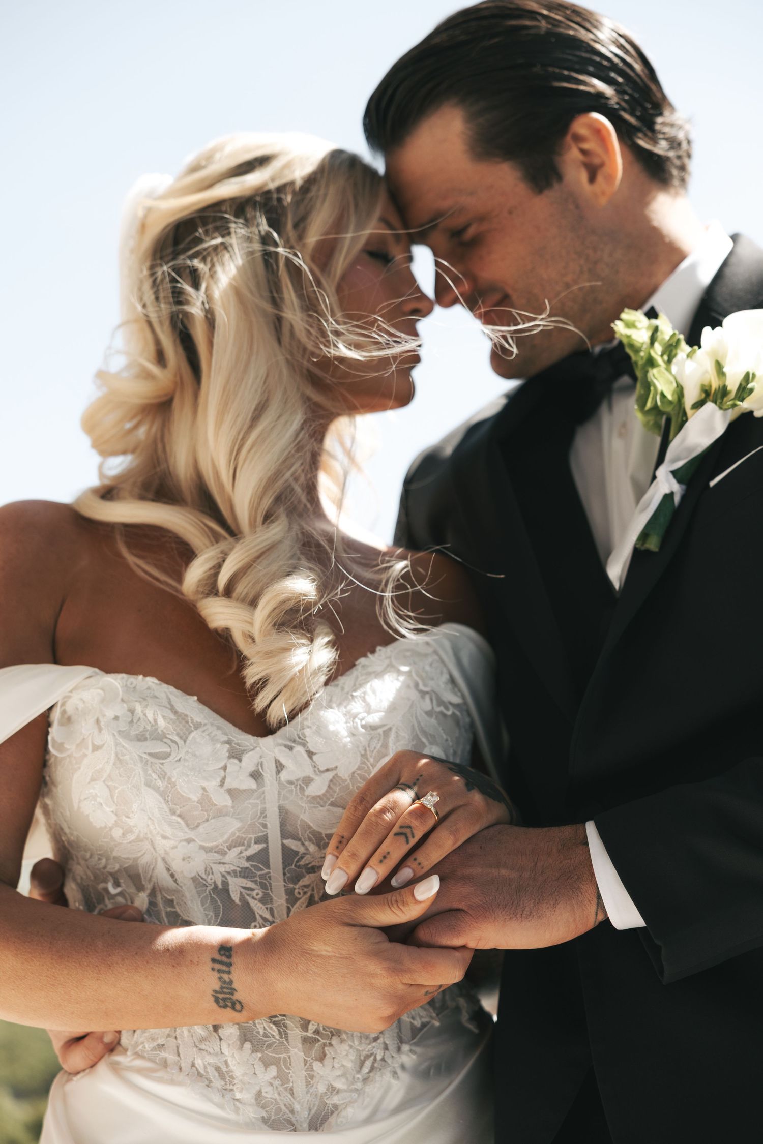 Bride and groom sharing a romantic forehead touch moment outdoors on their wedding day.