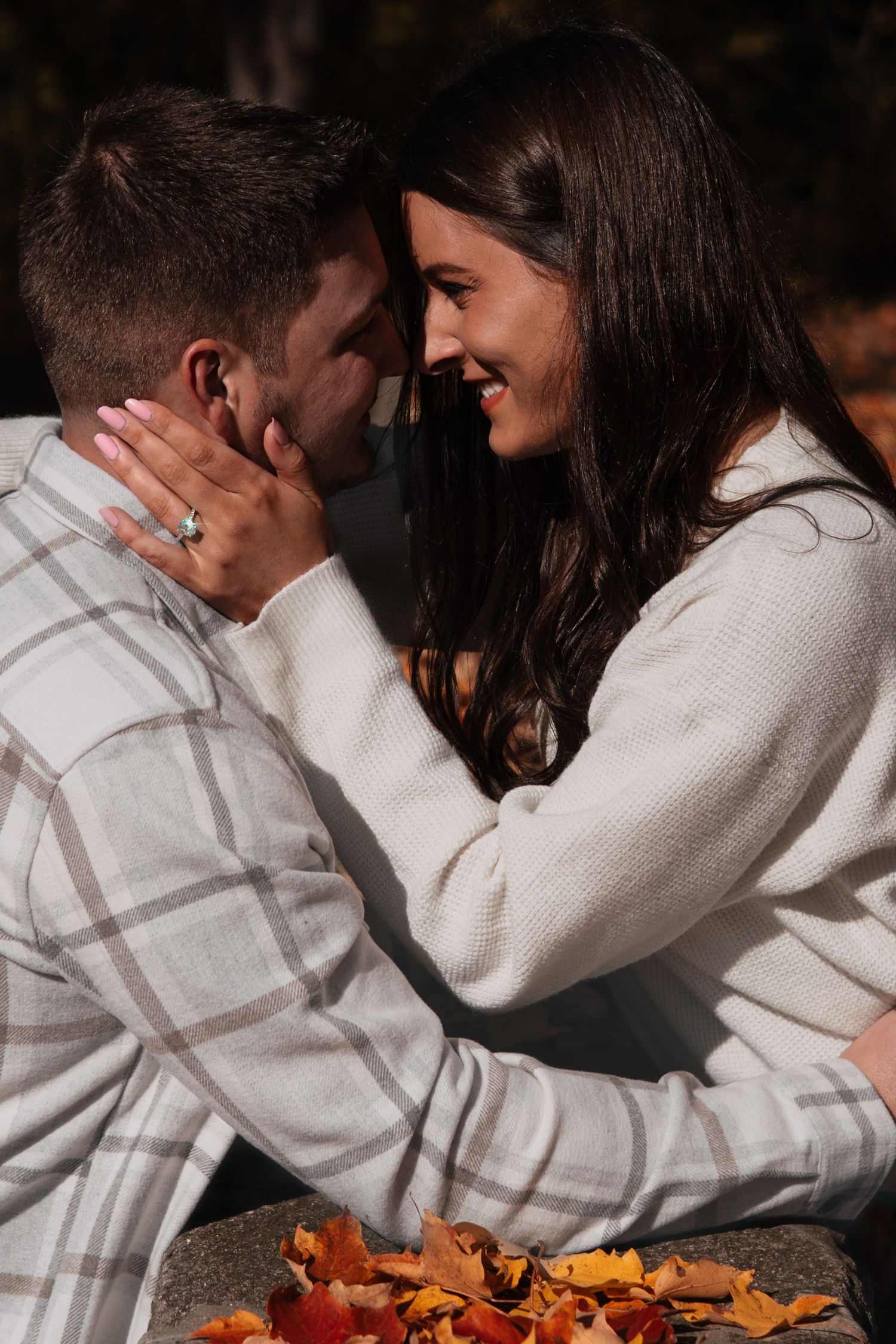 Happy couple sharing a tender forehead touch moment surrounded by colorful autumn leaves.