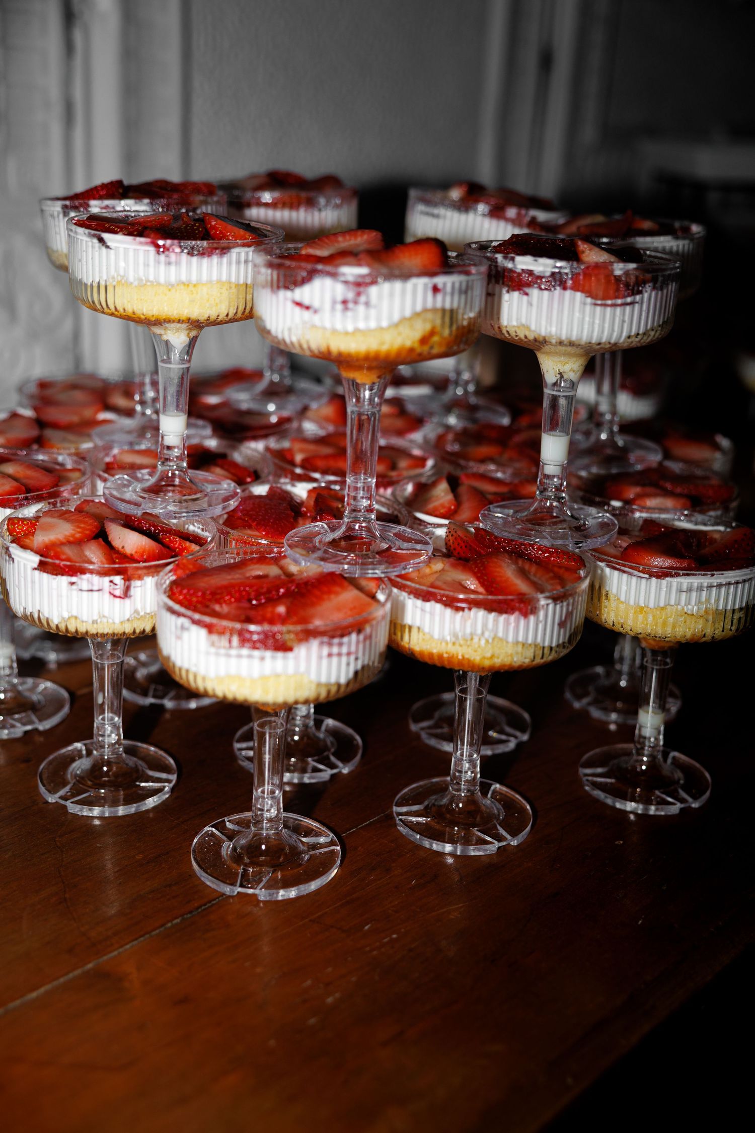 Elegant dessert cups filled with creamy cheesecake layers and fresh strawberry slices arranged in a pyramid display.