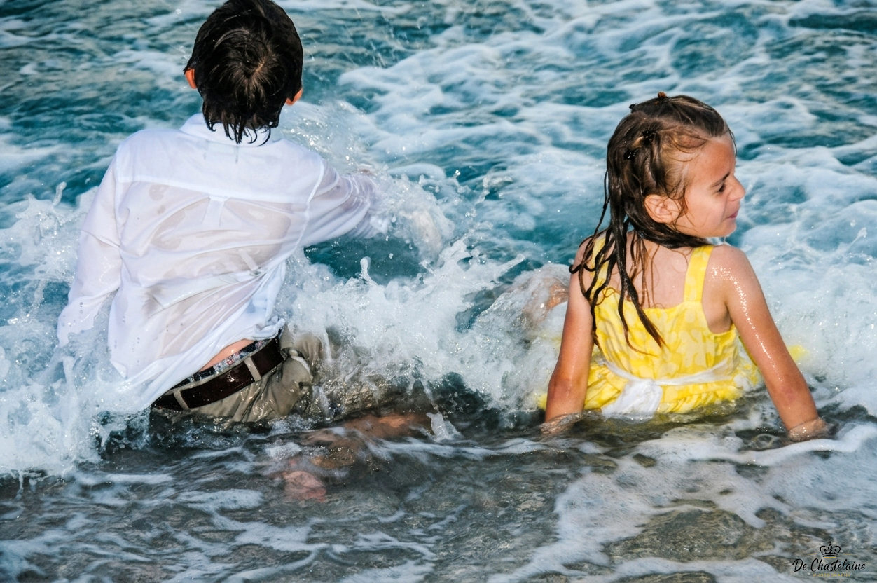 Two kids in clothes in the ocean