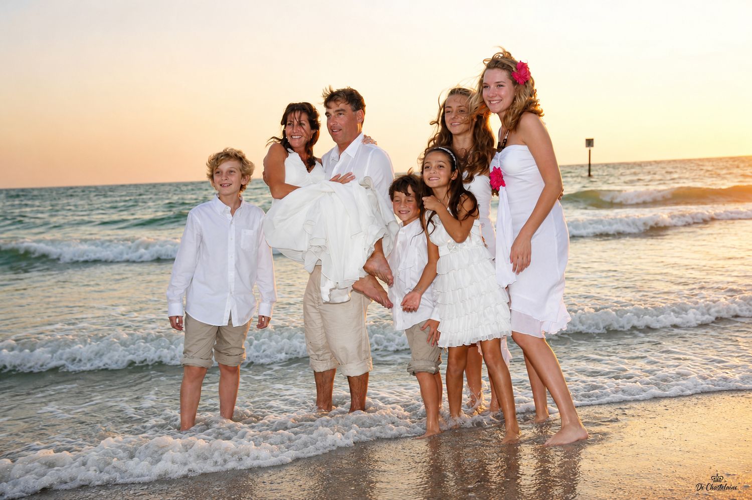 Beach wedding family with bride and groom in the ocean