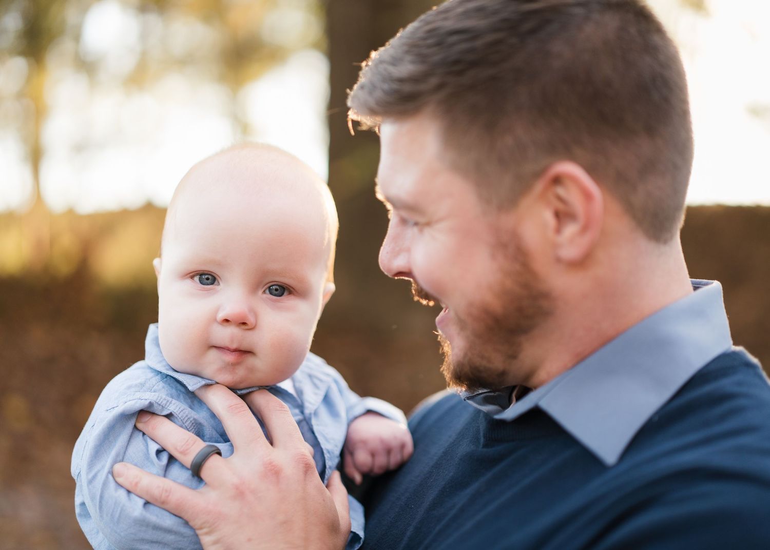 A father tenderly holds his infant baby boy outdoors in warm golden light in Chattanooga, TN.