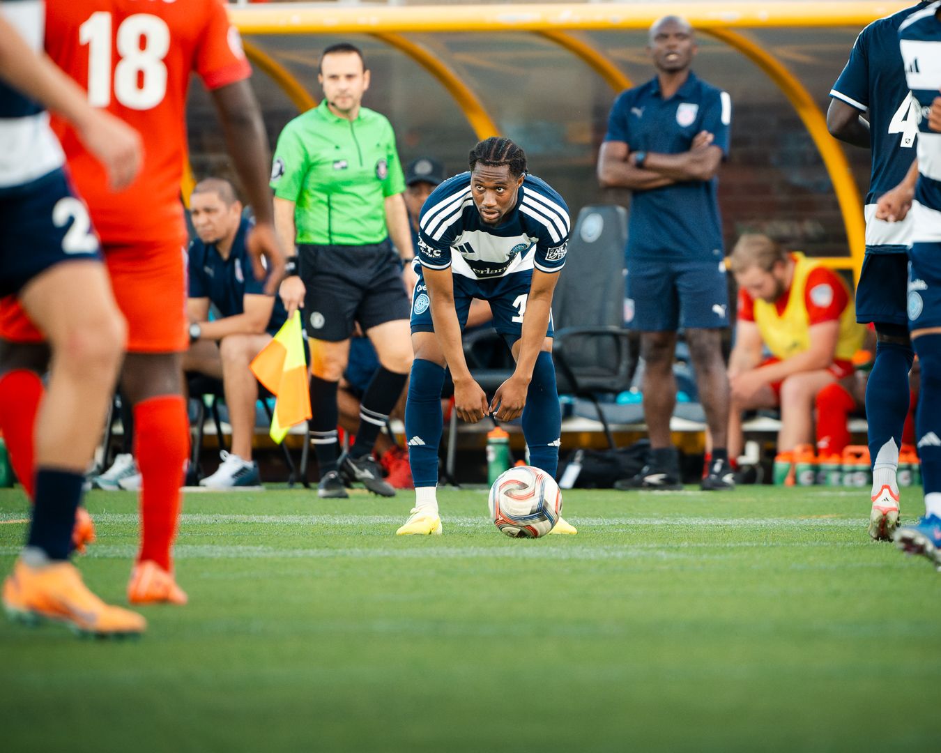 Chattanooga FC Soccer player in navy blue uniform prepares to take a free kick on a green turf field.