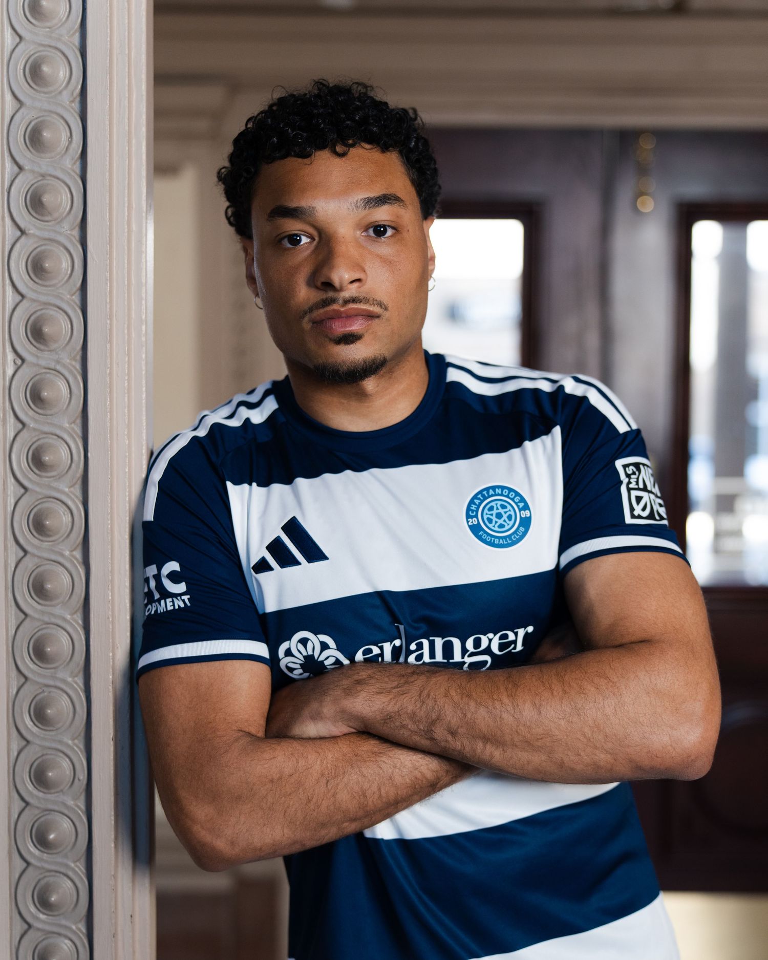 Chattanooga FC player poses with arms crossed wearing soccer jersey indoors photographed for a creative sports assignment in Chattanooga, TN