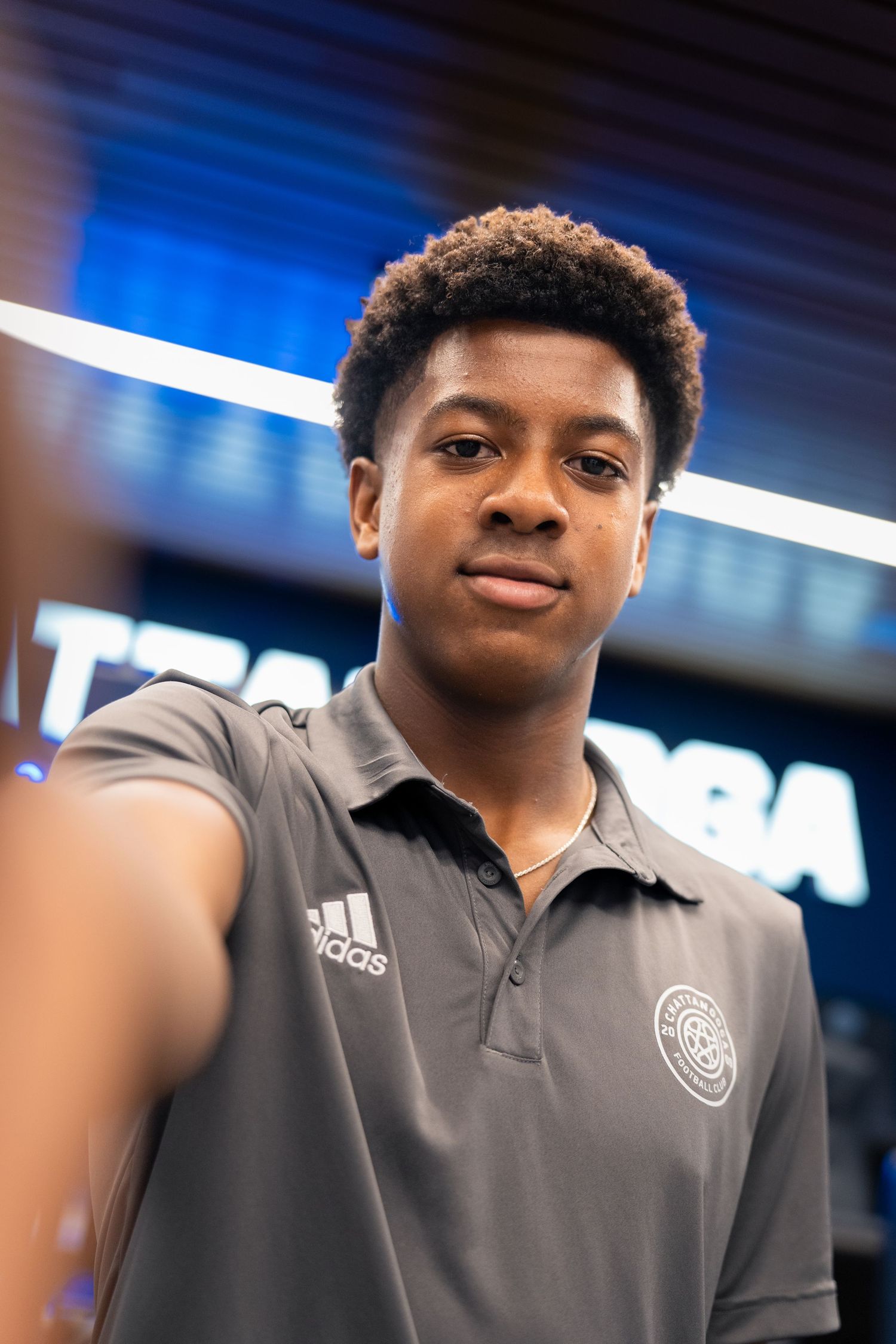 Young soccer player in gray polo shirt takes a selfie at a professional sports facility Photographed for Chattanooga FC player signing.